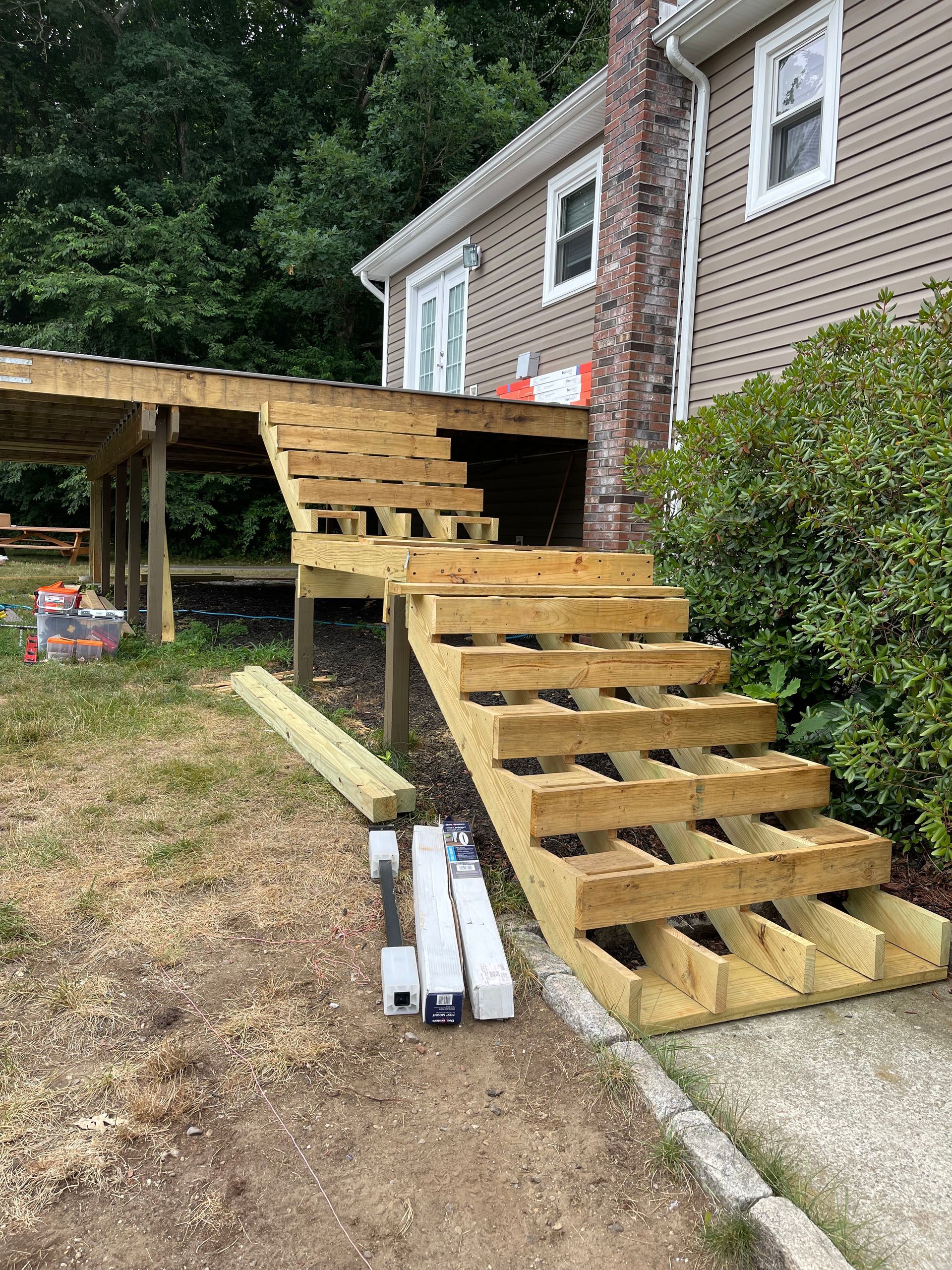 Wooden deck and stairs under construction next to a beige house.