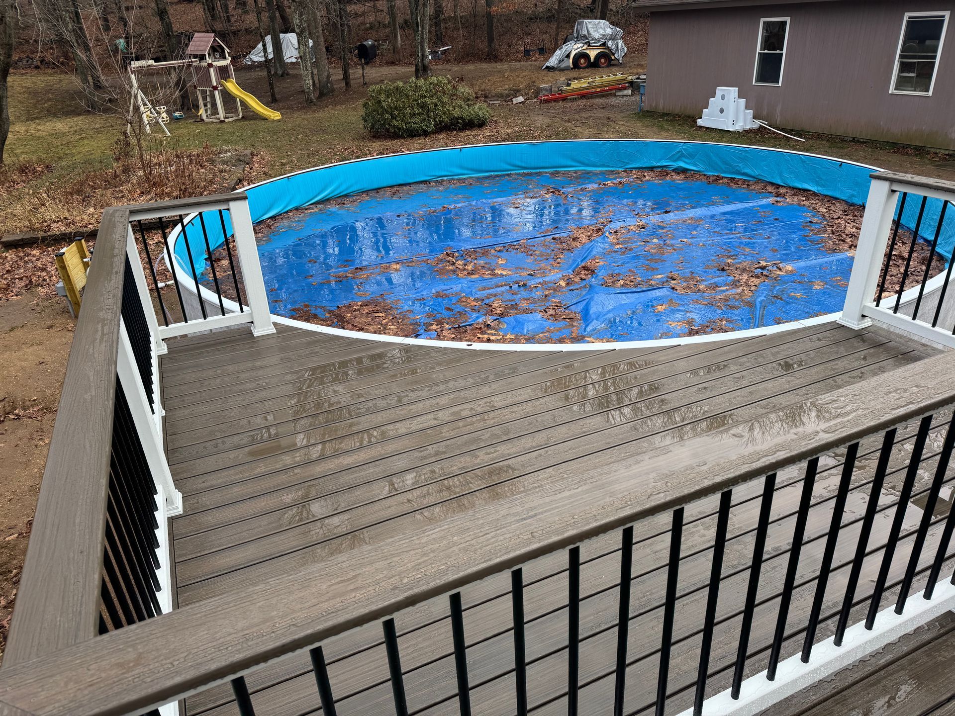 A deck overlooking a covered circular pool with leaves.