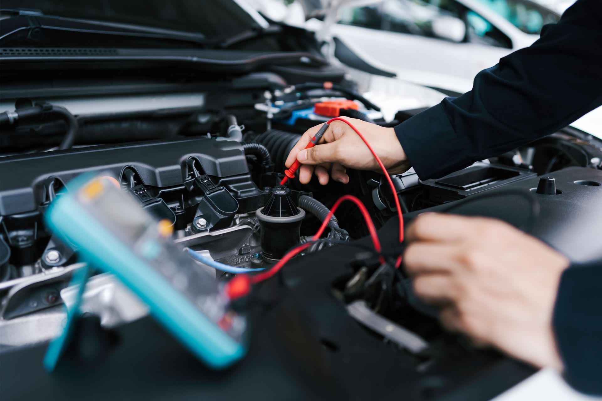 Mechanic testing a car battery with a multimeter in an open engine bay