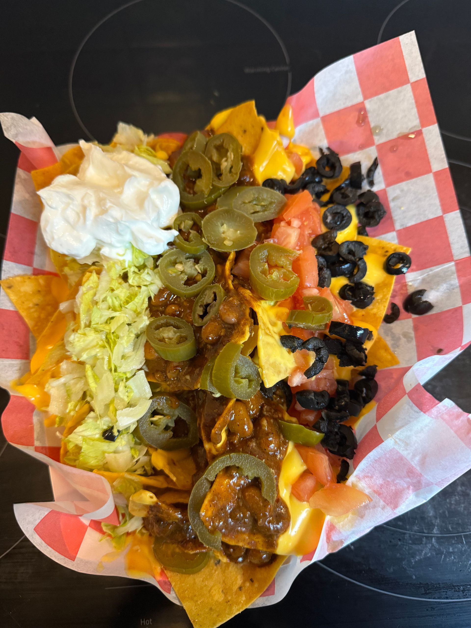 A close up of a tray of nachos on a checkered paper