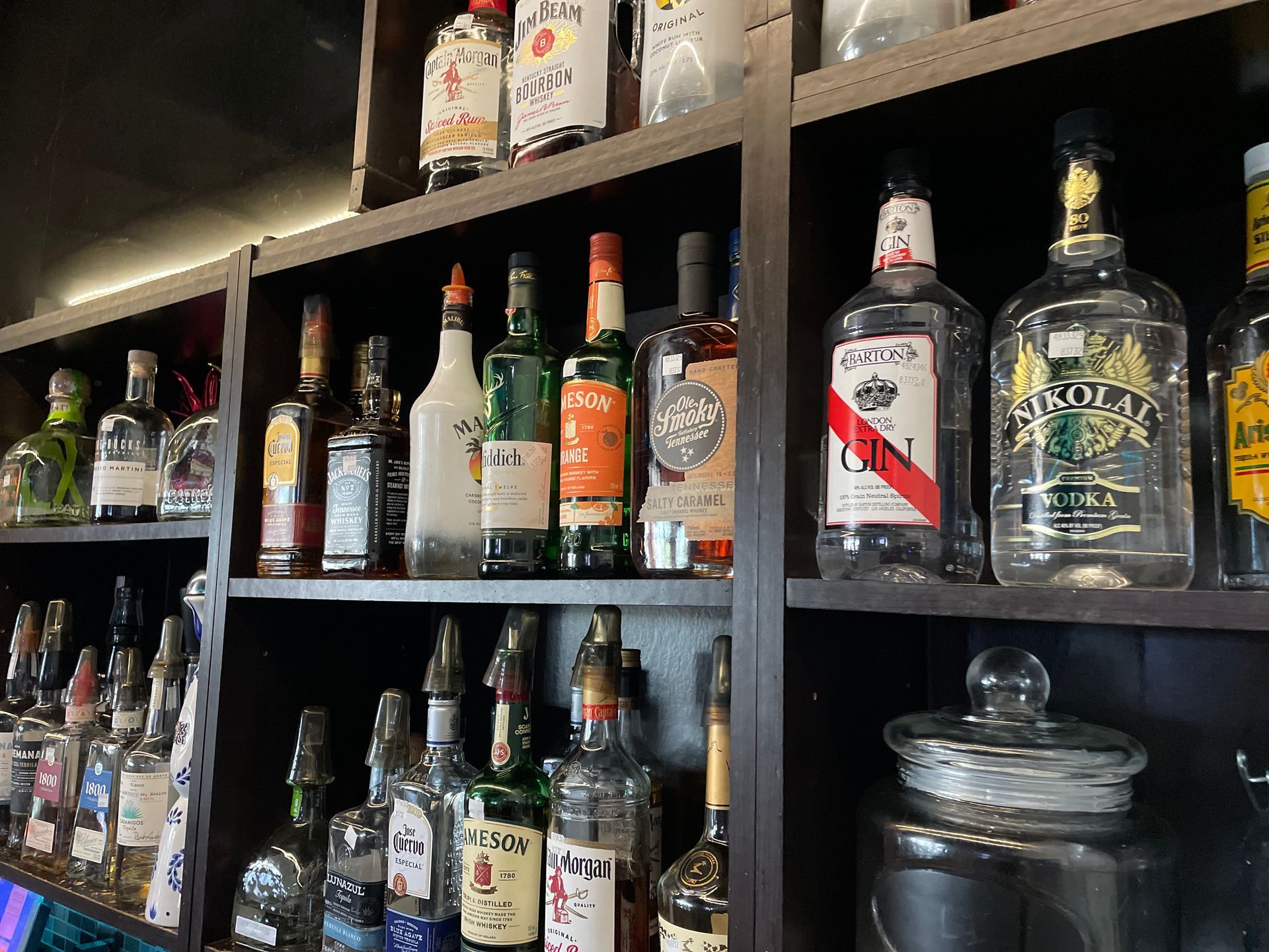 A shelf filled with lots of bottles of alcohol.