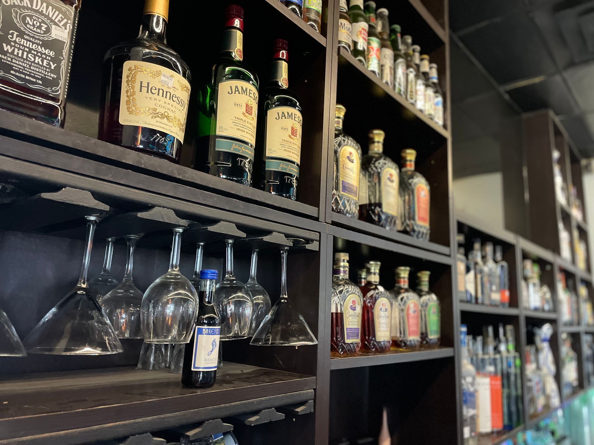 A shelf filled with bottles of liquor and wine glasses.