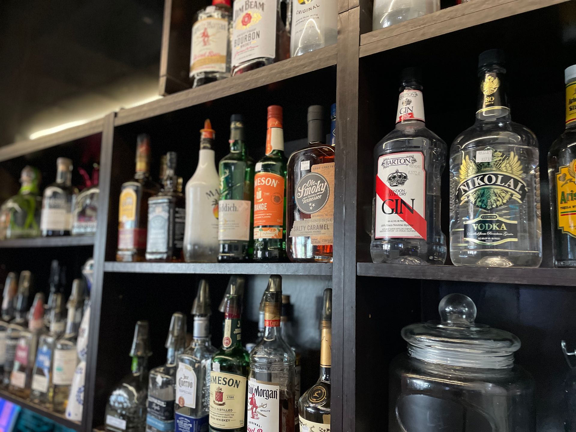 A bar filled with lots of bottles of liquor on shelves.