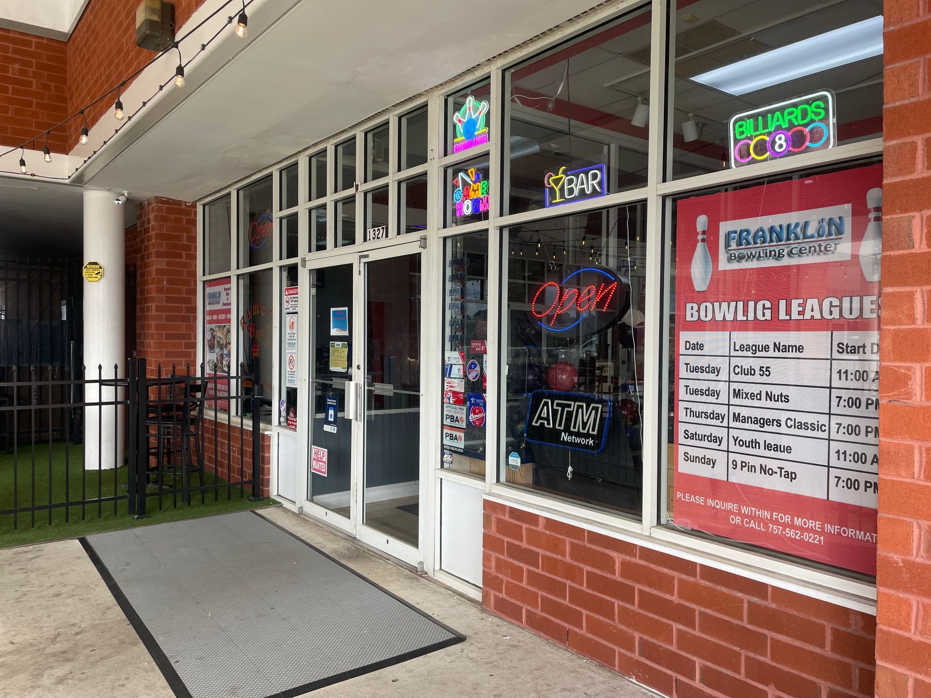 The front of a bowling alley with a sign on the window that says `` bowling league ''.