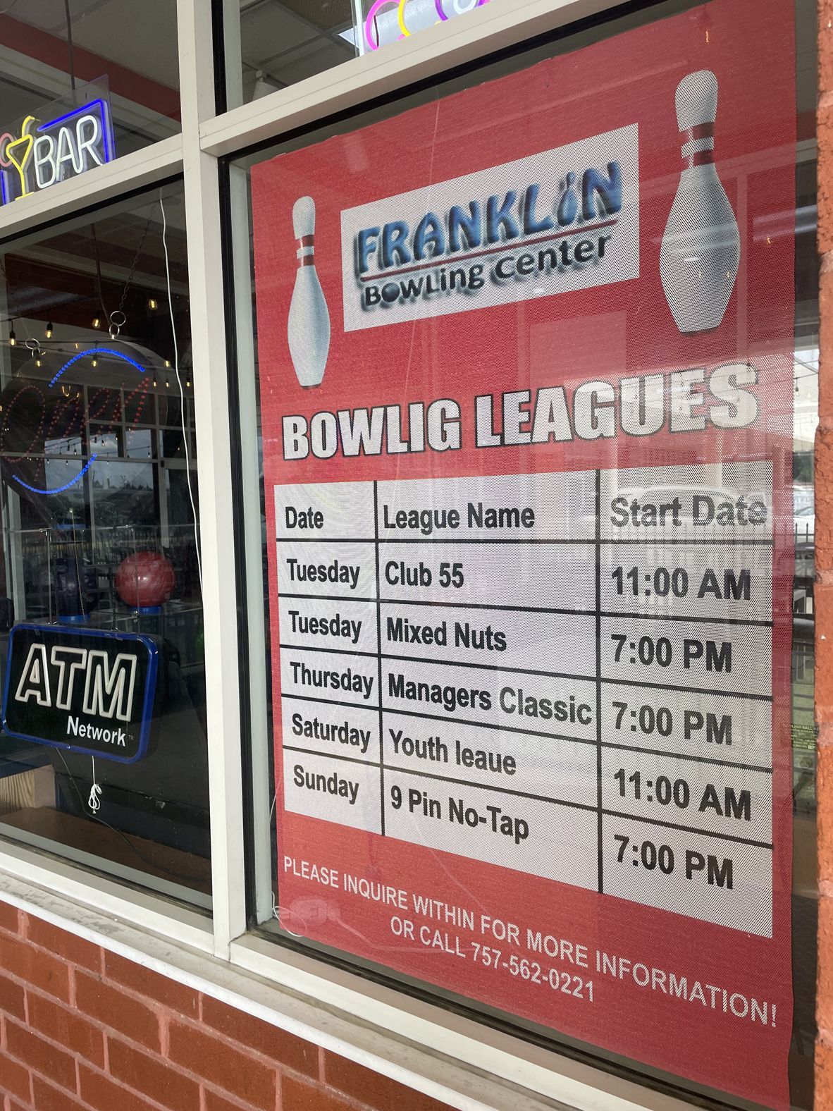 A sign in a window advertising bowling leagues.