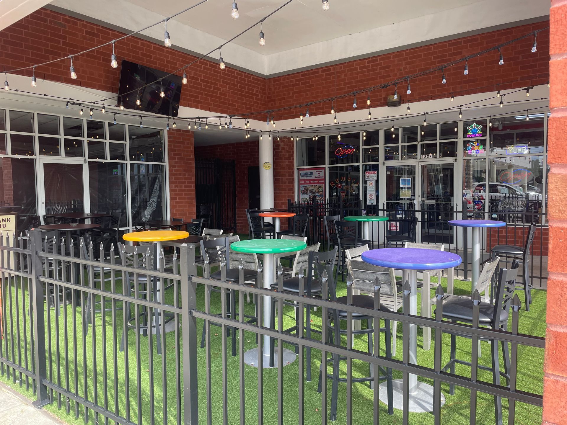 A restaurant with tables and chairs behind a fence.
