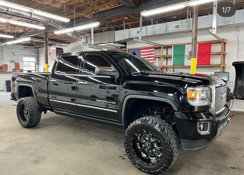 Black lifted GMC pickup truck in an industrial warehouse, shown in side view.