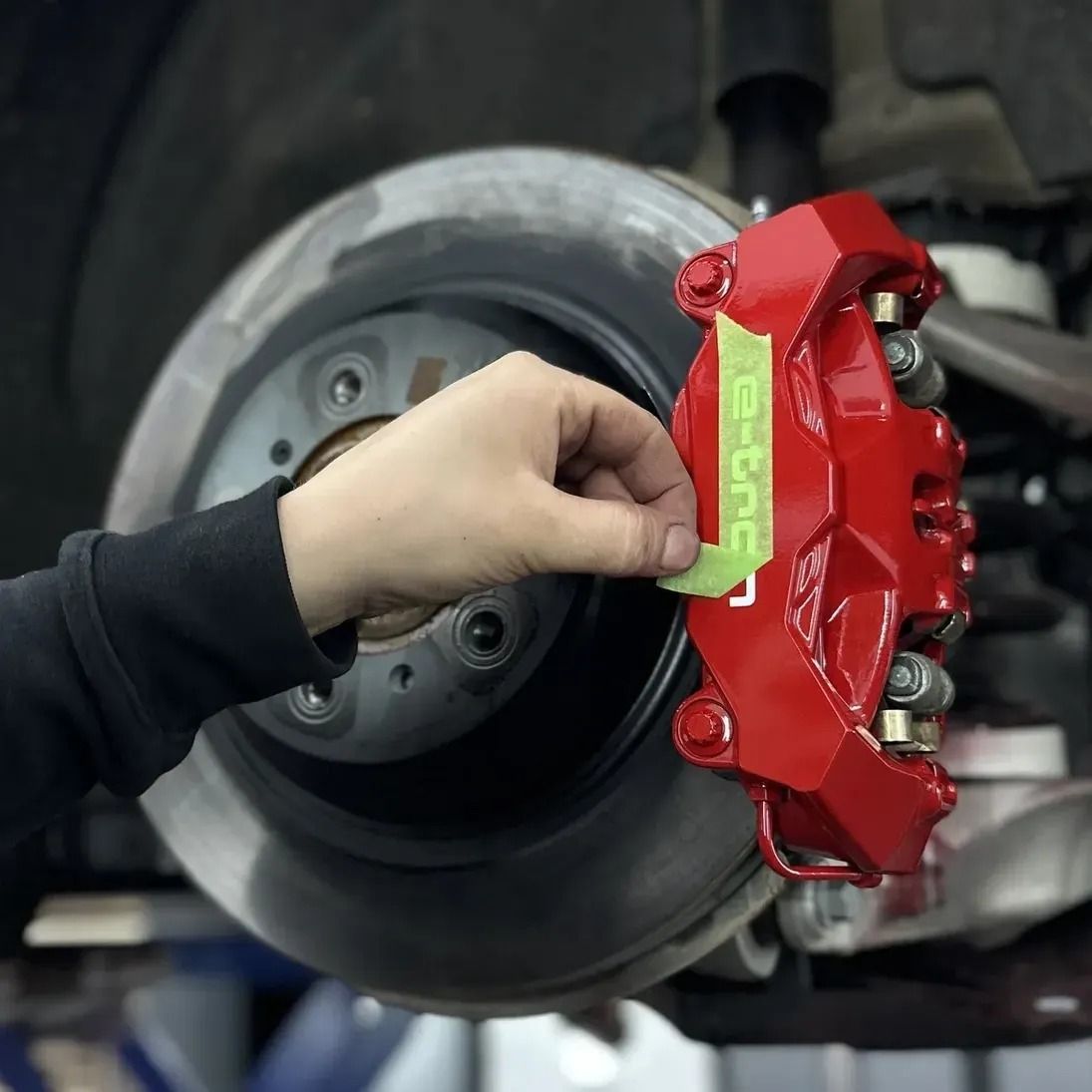 Hand installing a red Brembo brake caliper onto a car wheel assembly