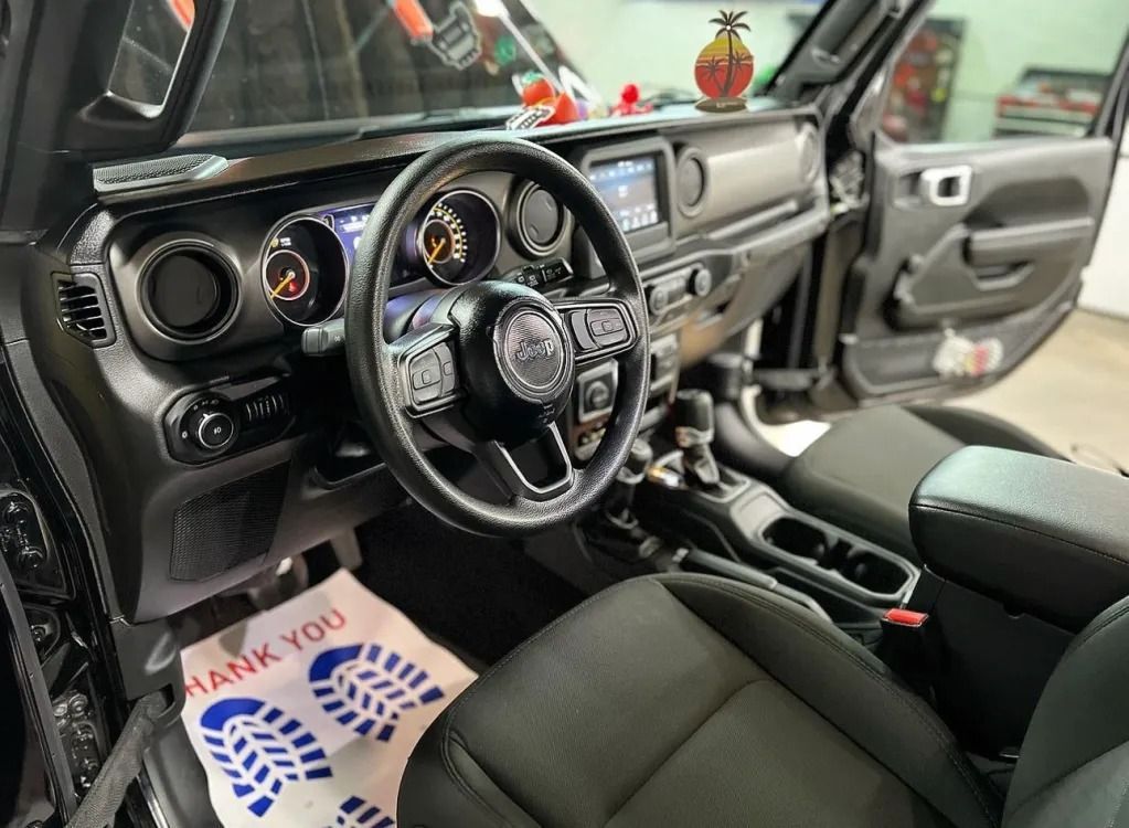 Custom black car interior with steering wheel, dashboard gauges, and center console; open door visible