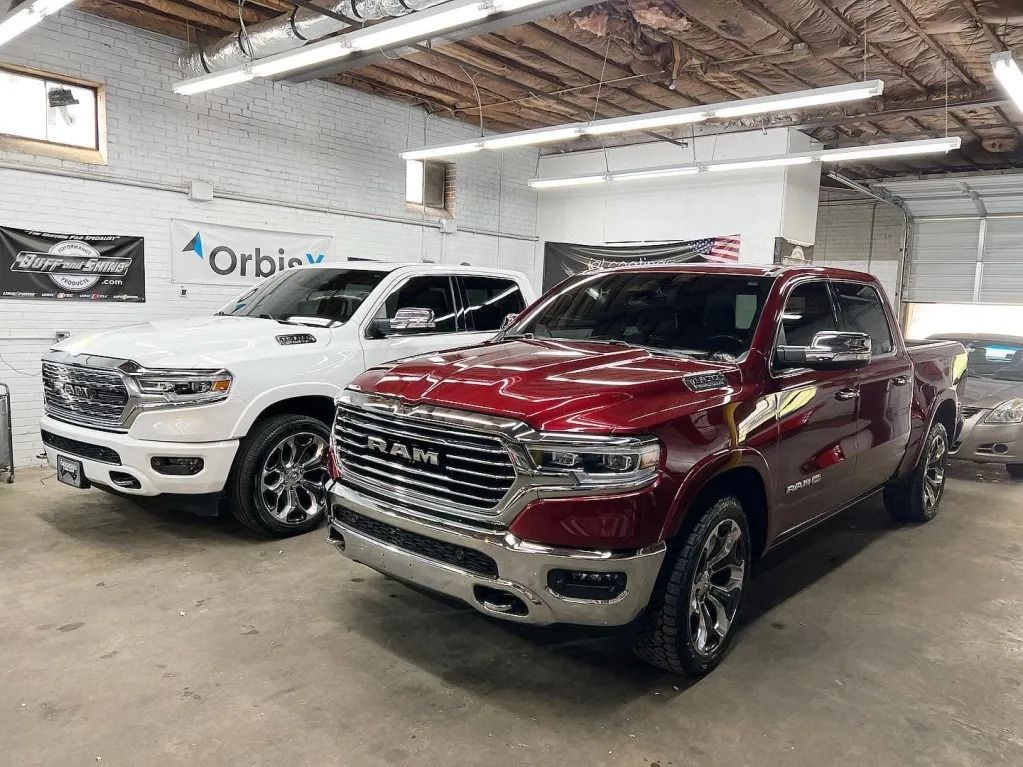 Two pickup trucks, one white and one red, parked inside a garage showroom