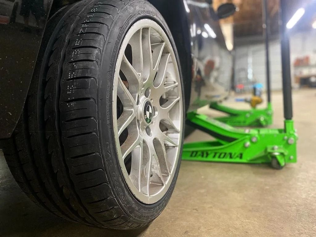 Car wheel on a floor jack in a garage, showing a tire being lifted for repair