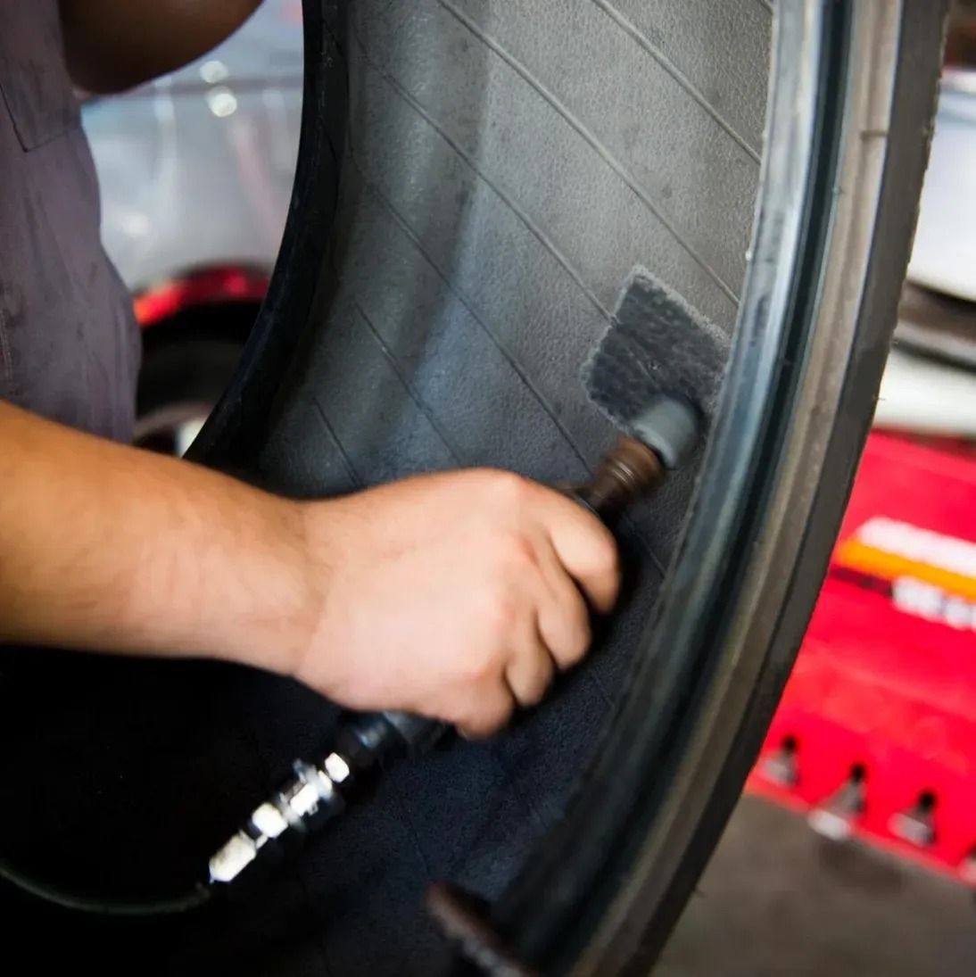 Hand cleaning a car tire’s inner rim with a cloth or brush