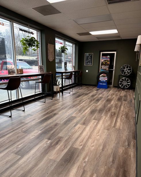 Interior with wood flooring, black chairs, large windows, and a wall mirror.