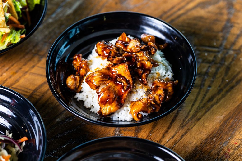 A bowl of chicken and rice on a wooden table.