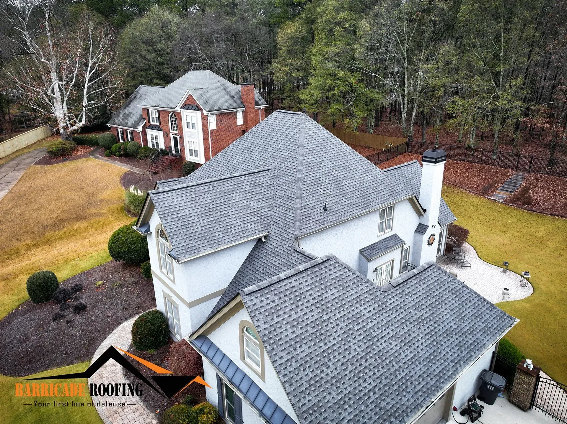 Aerial view of two-story houses with gray shingle roofs, surrounded by trees and greenery.