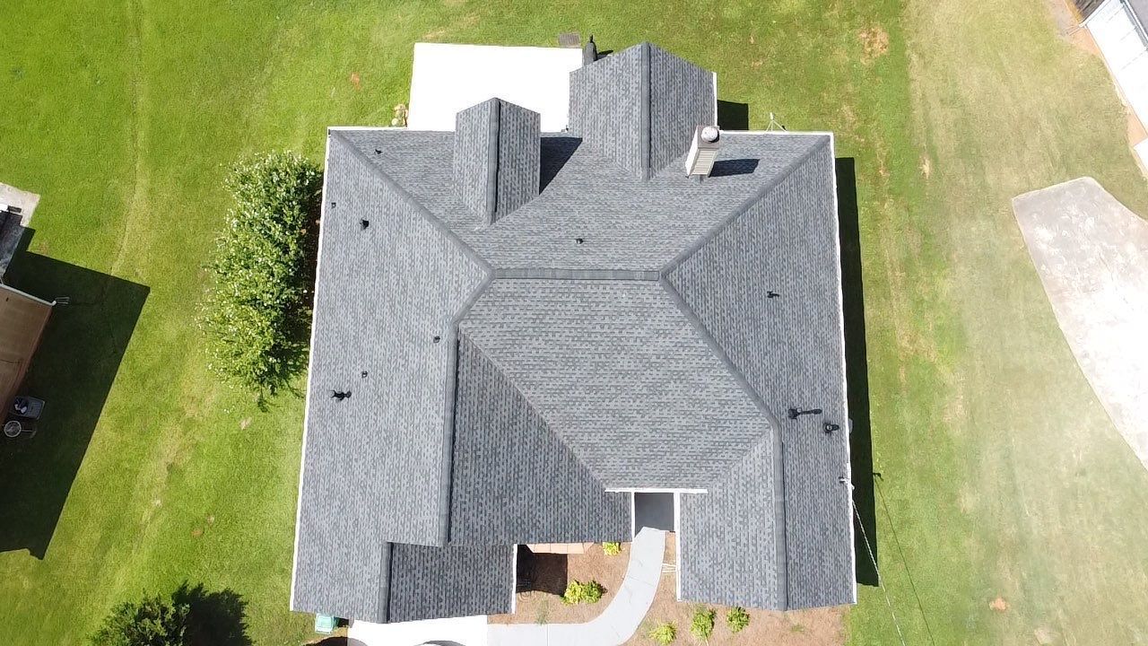 Overhead view of a house with a gray shingled roof, set on green grass.