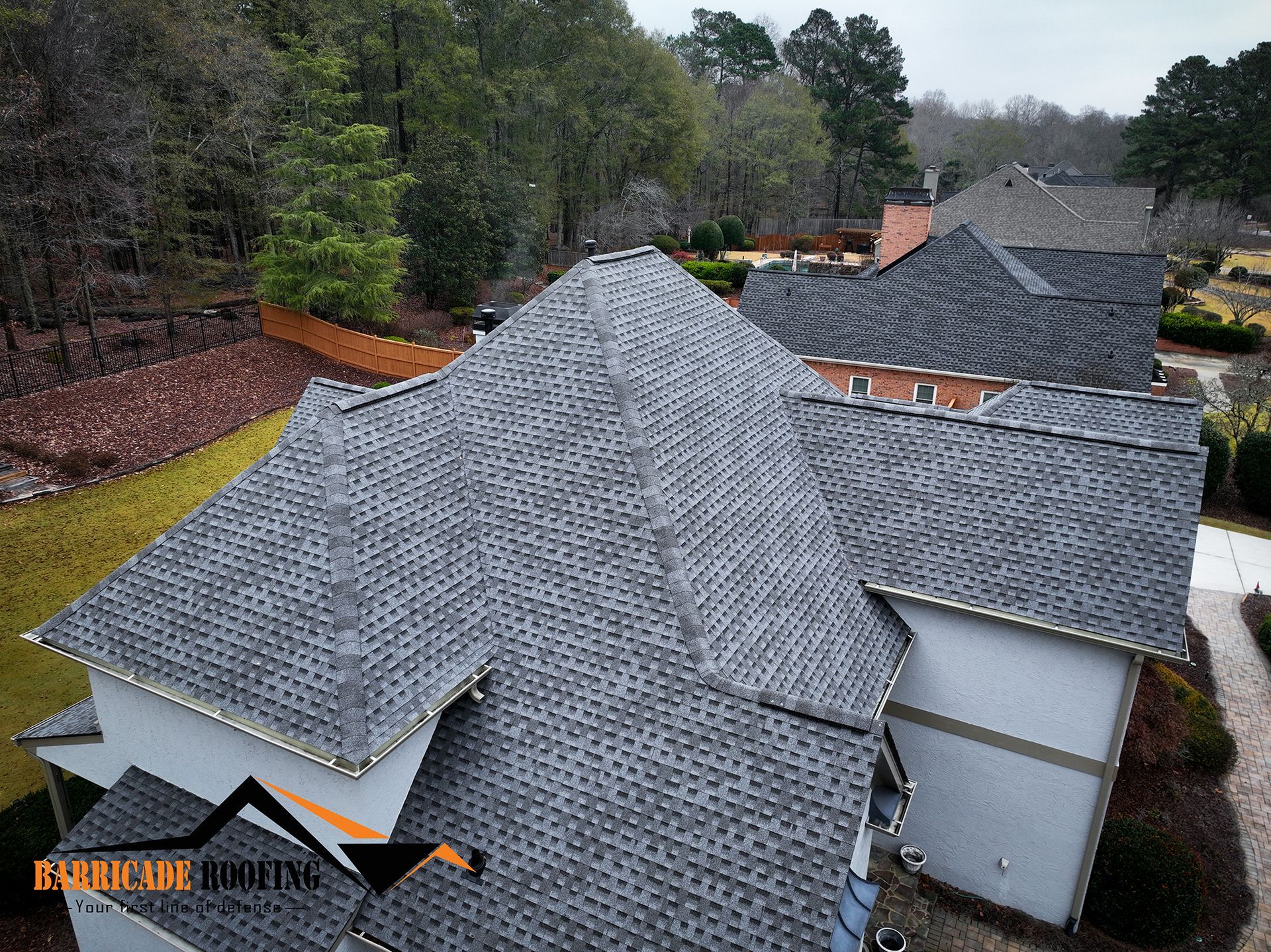 Overhead view of a house with gray shingle roof in a wooded area.