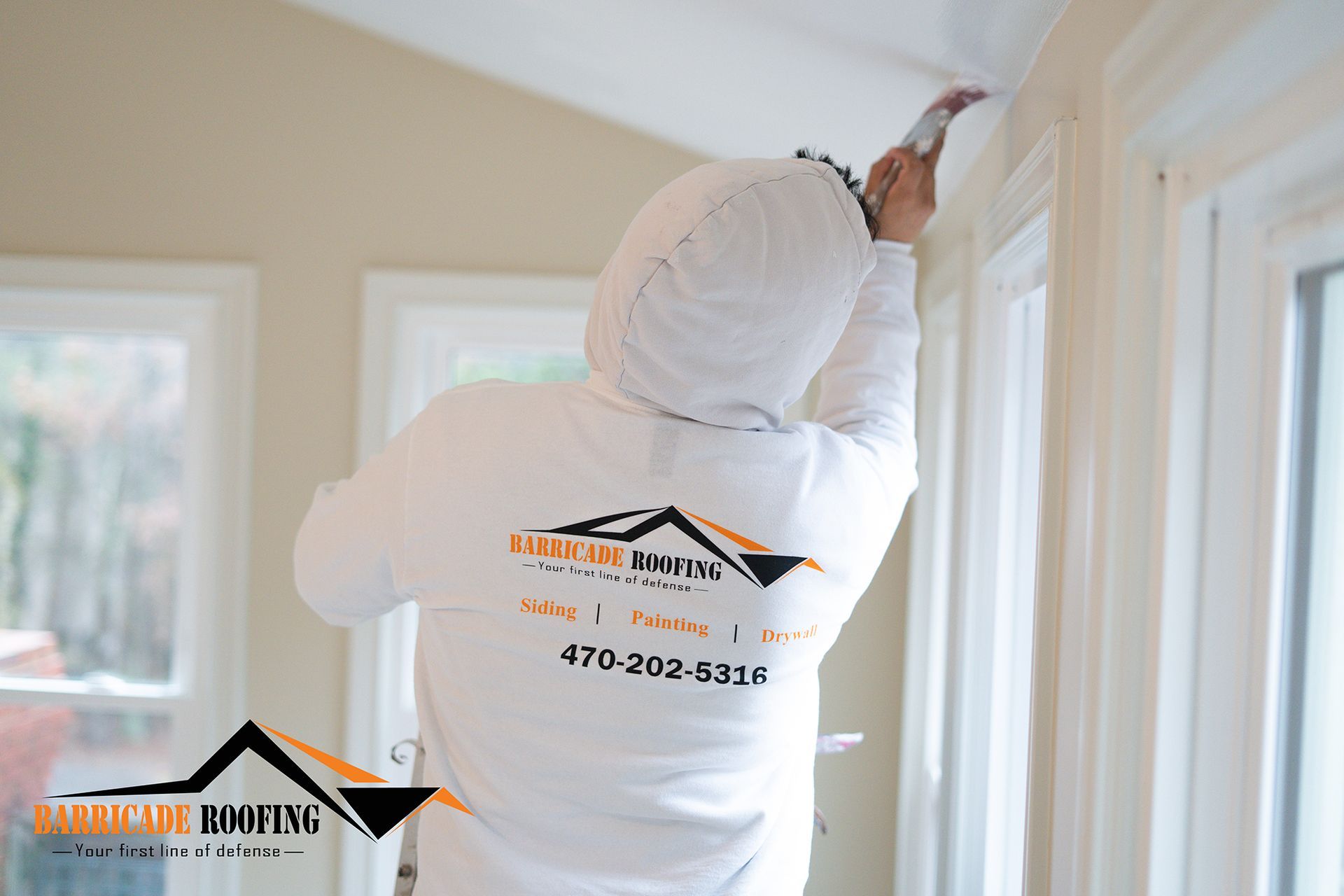 Person in protective suit painting window trim. Inside, light beige walls, bright white trim.