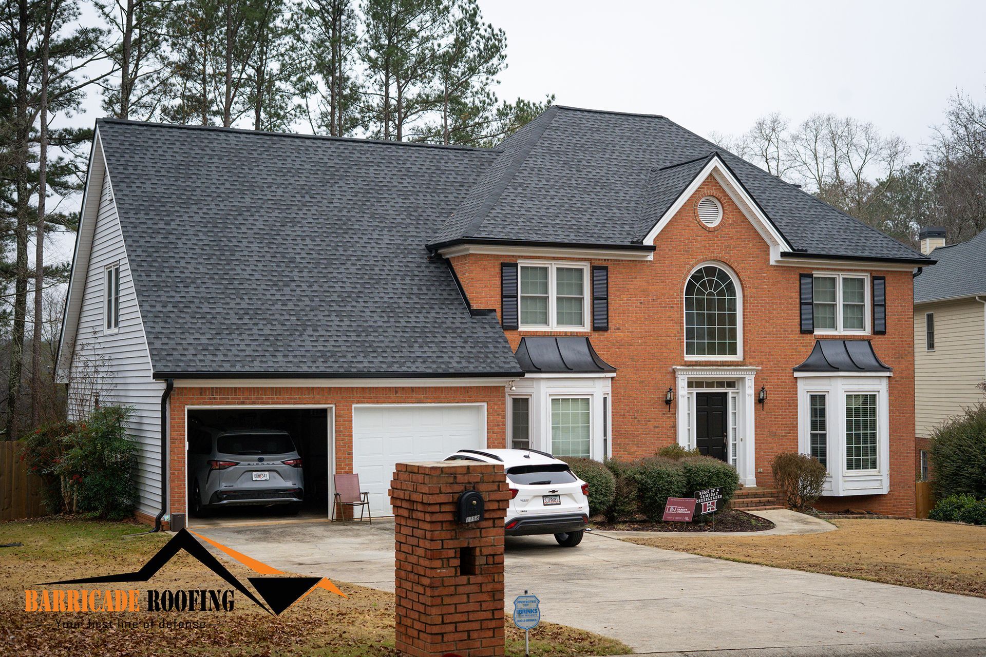 Brick house with a dark gray roof, two-car garage, and a parked car in the driveway.
