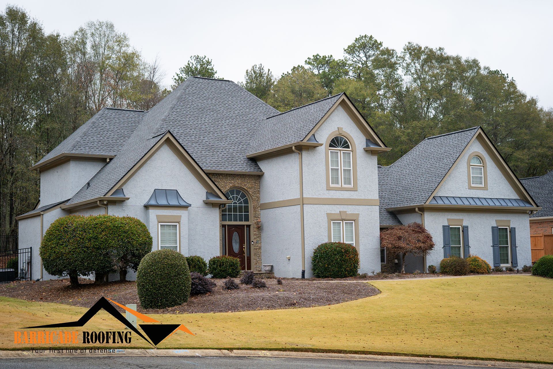 House with gray roof, light blue siding, brown trim, and bushes in the front yard.