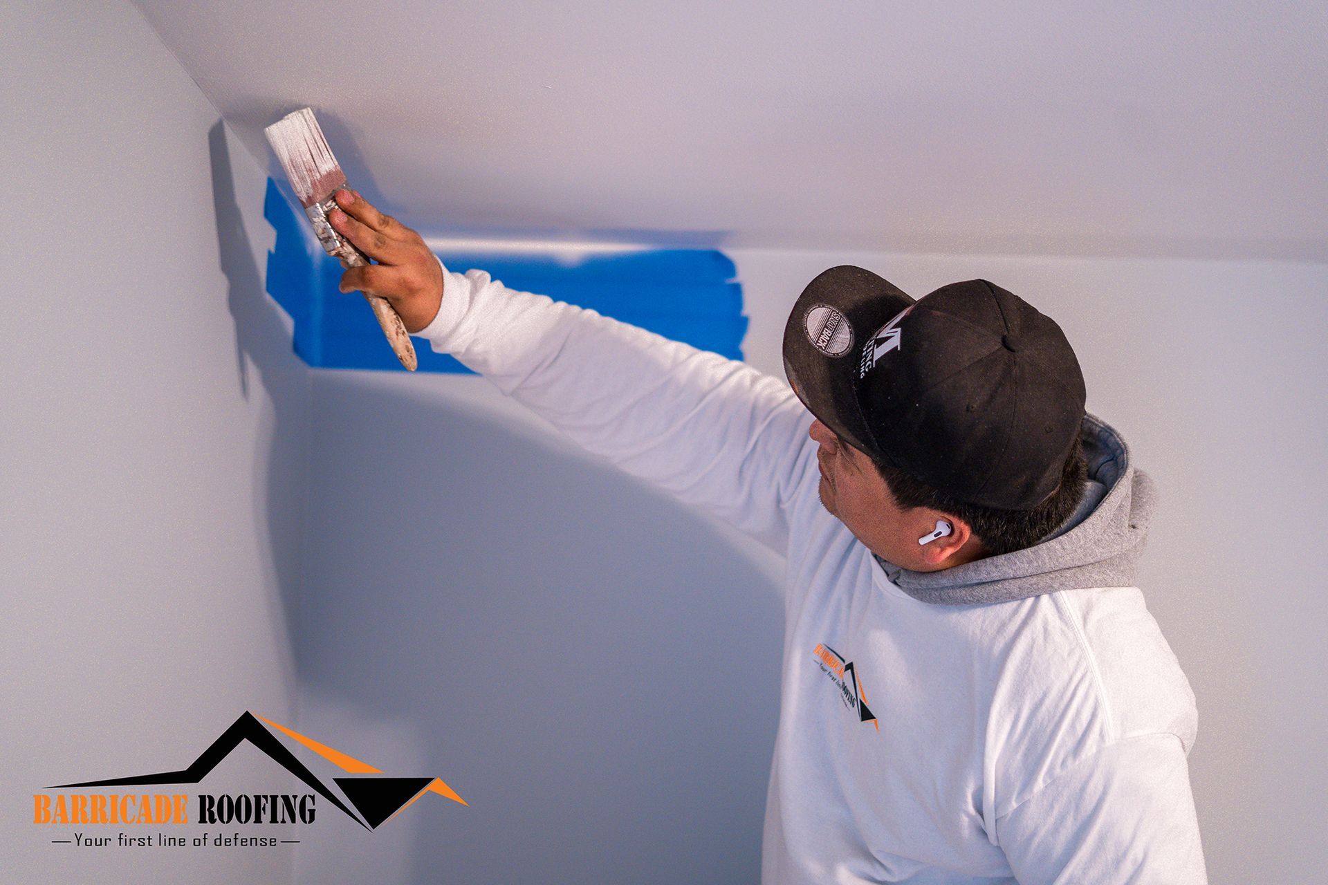 Person in white shirt, painting blue paint on the wall.