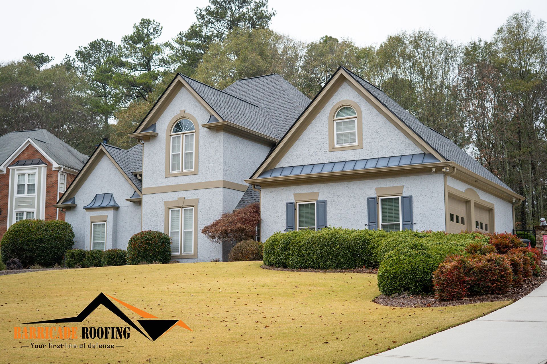 Gray stucco house with blue shutters, tan trim, and a lawn.