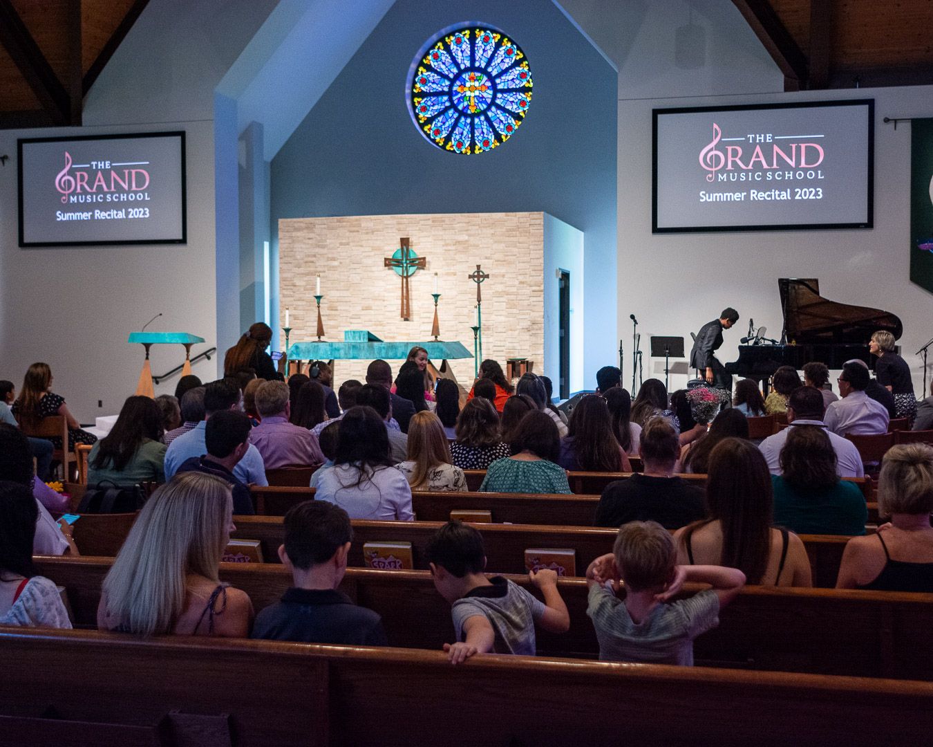 A large group of people are sitting in a church watching a concert.
