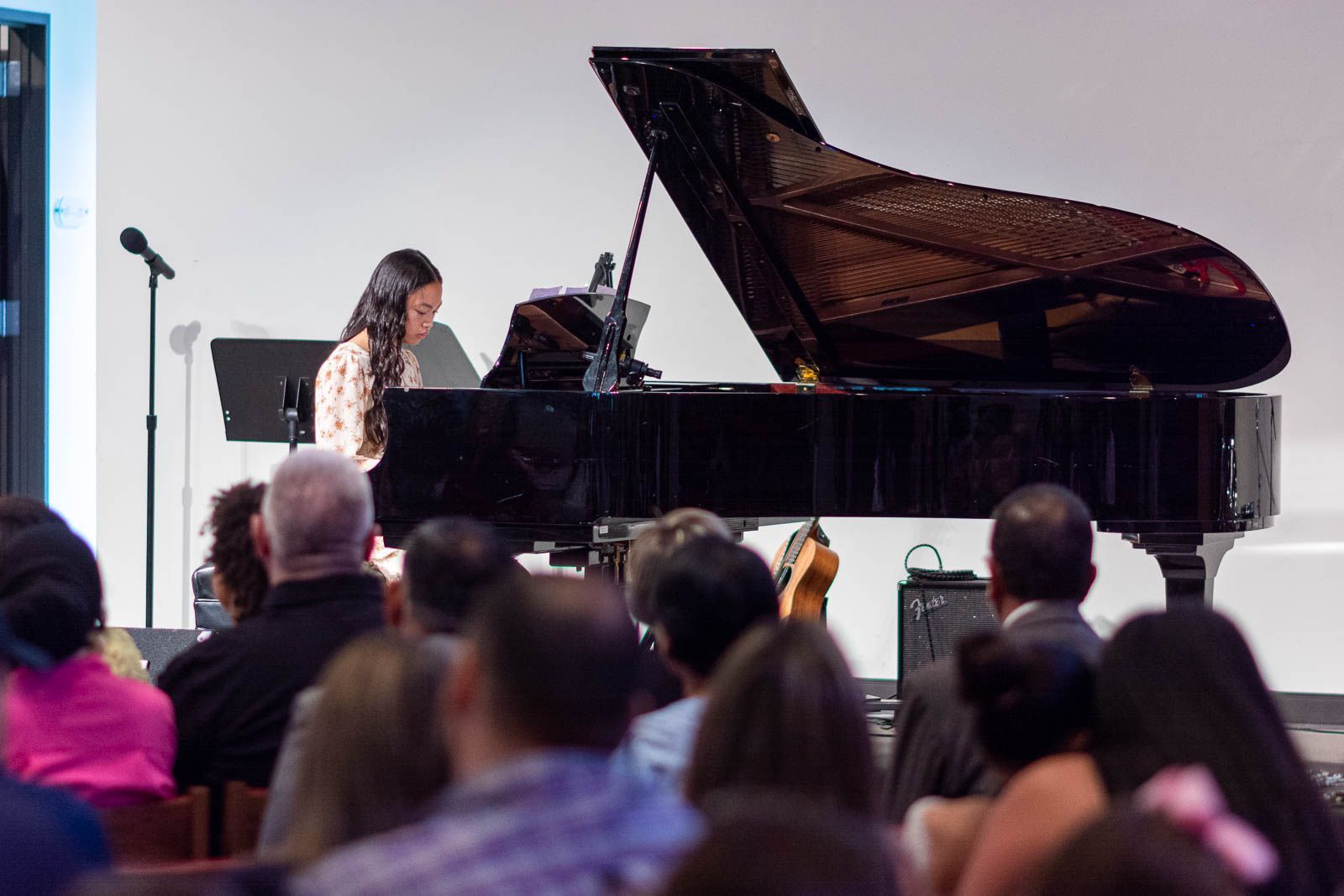 A woman is playing a piano in front of a crowd of people.