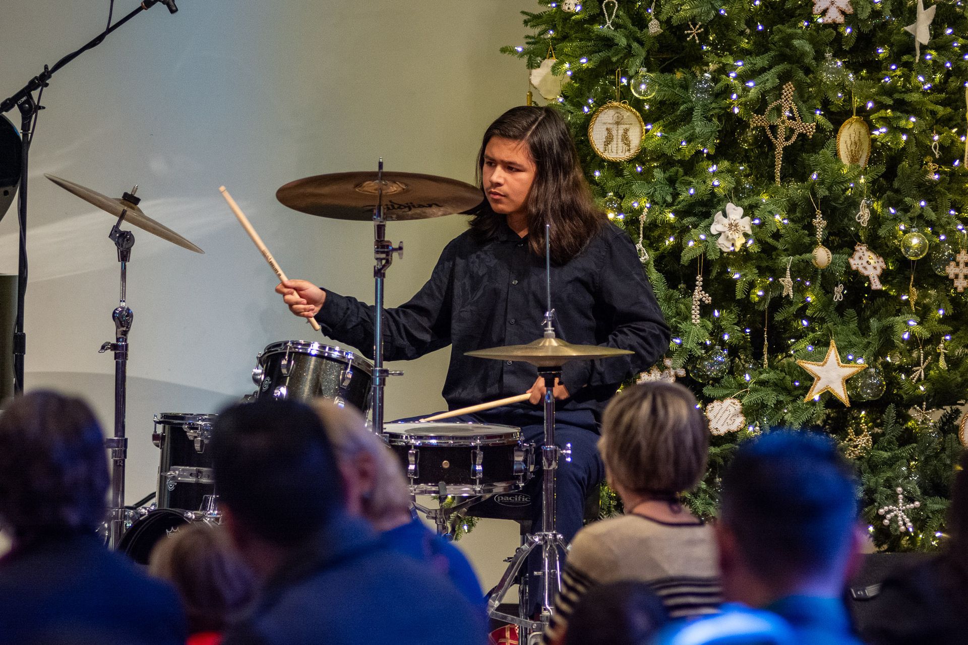 A man is playing drums in front of a christmas tree