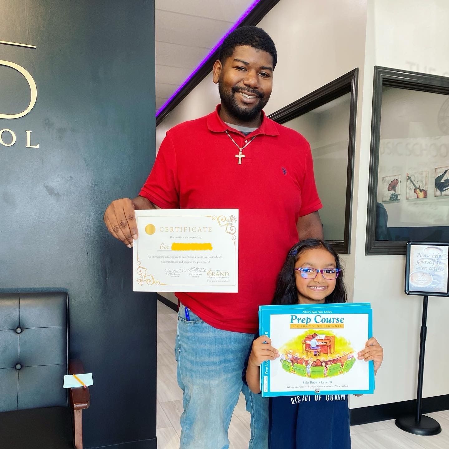 A man and a little girl are holding a certificate and a book