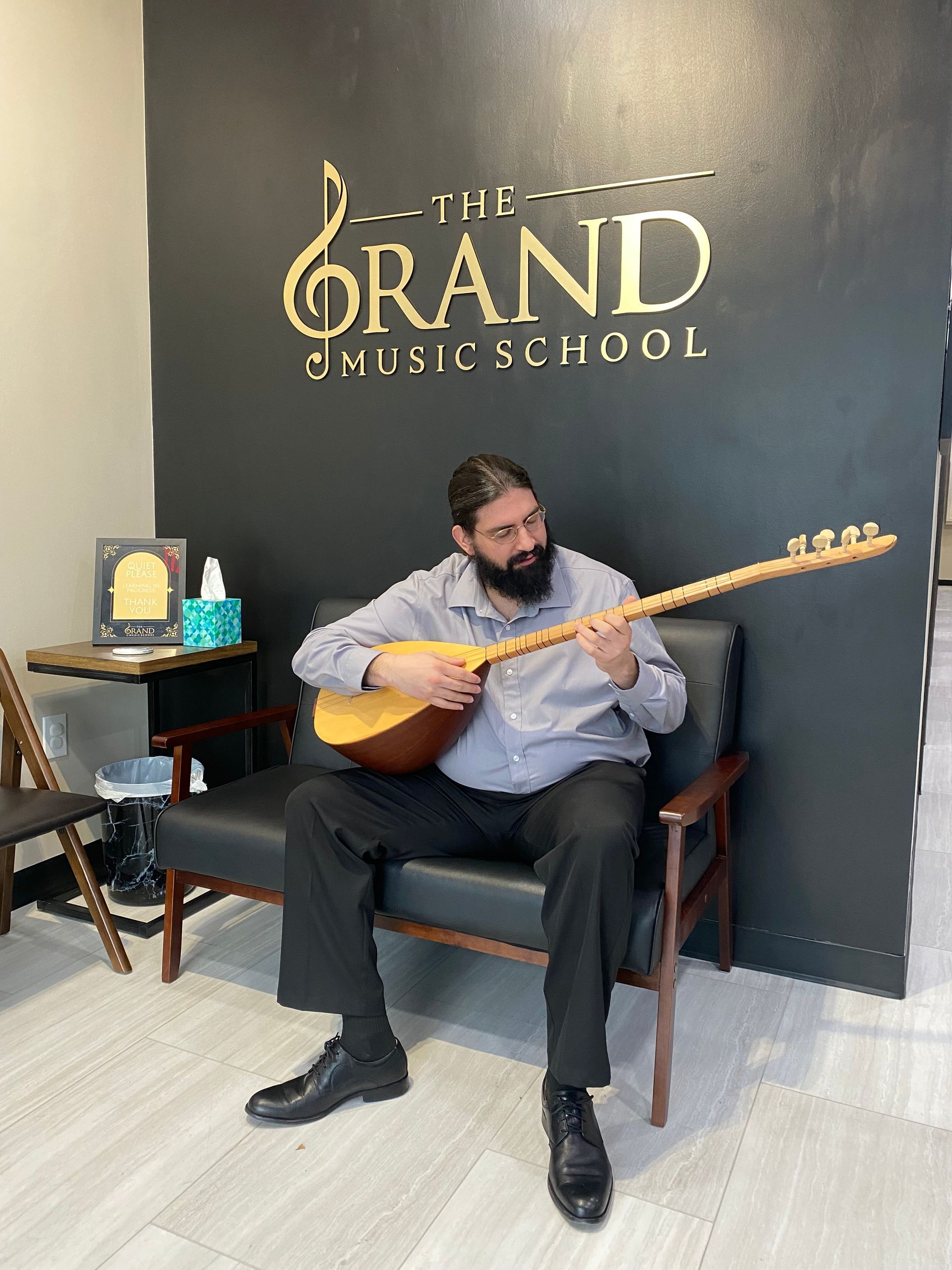 A man with a beard is sitting in a chair playing a guitar.