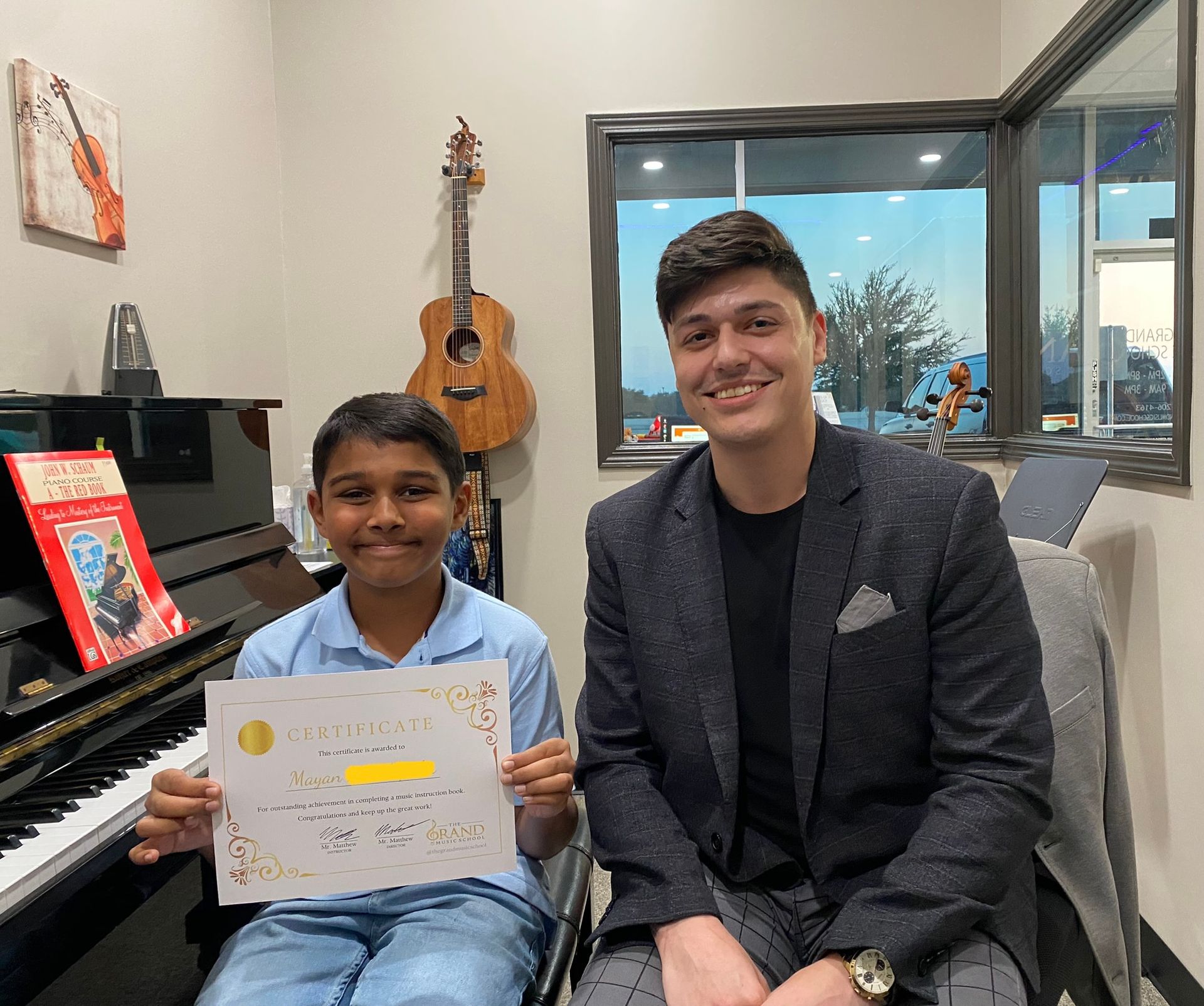 A man and a boy are sitting in front of a piano holding a certificate.