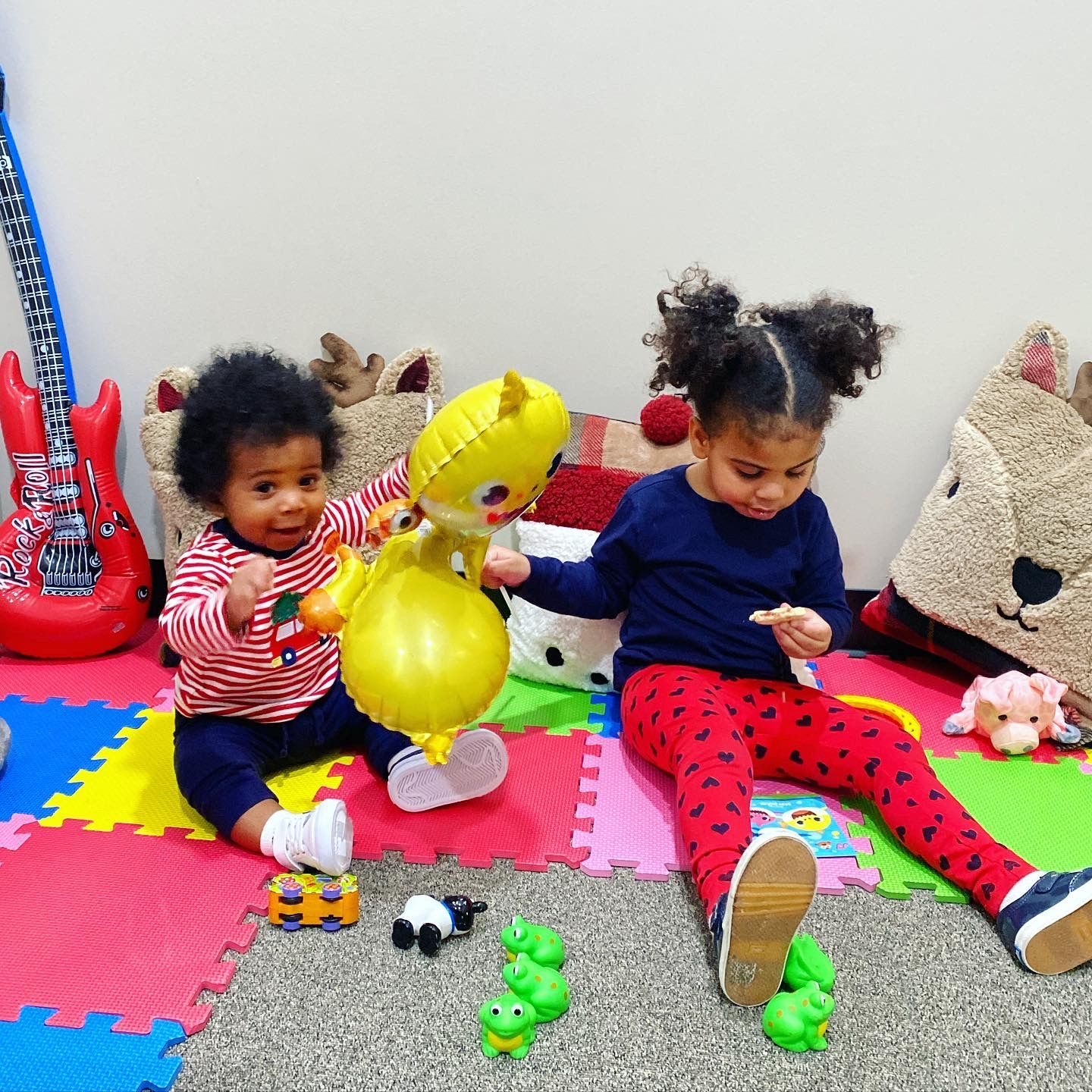 Two children are sitting on the floor playing with toys.