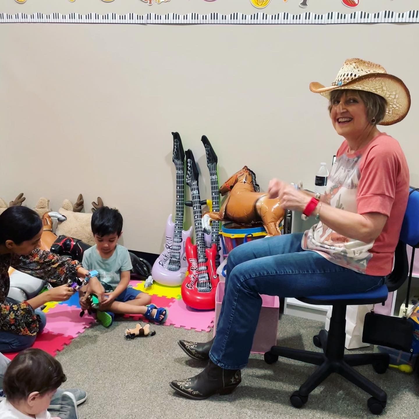 A woman in a cowboy hat sits in a chair with children