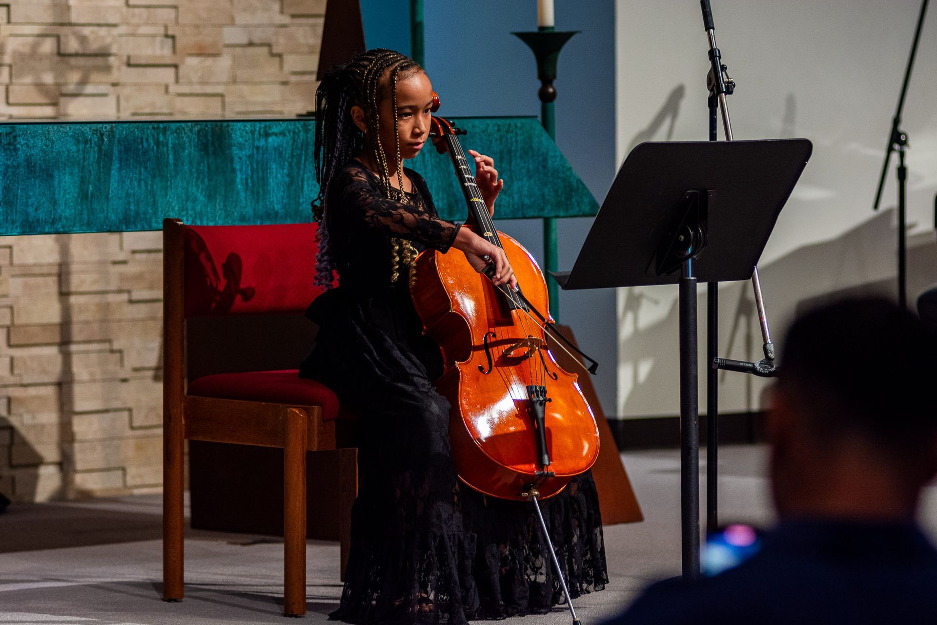 A young girl is playing a cello in a church.