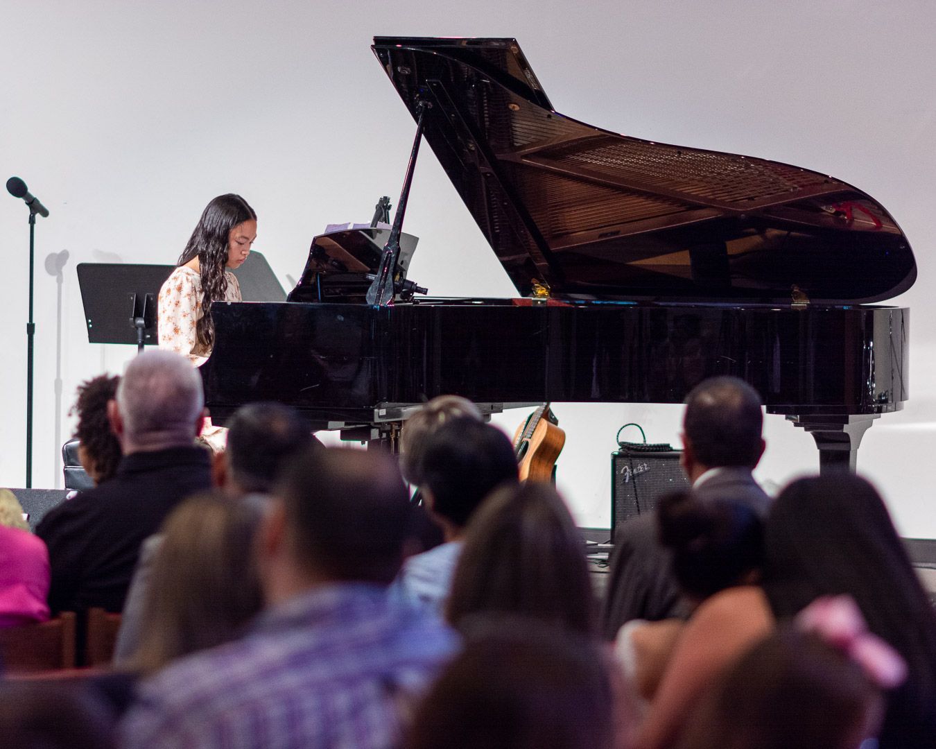 A woman is playing a piano in front of a crowd of people.
