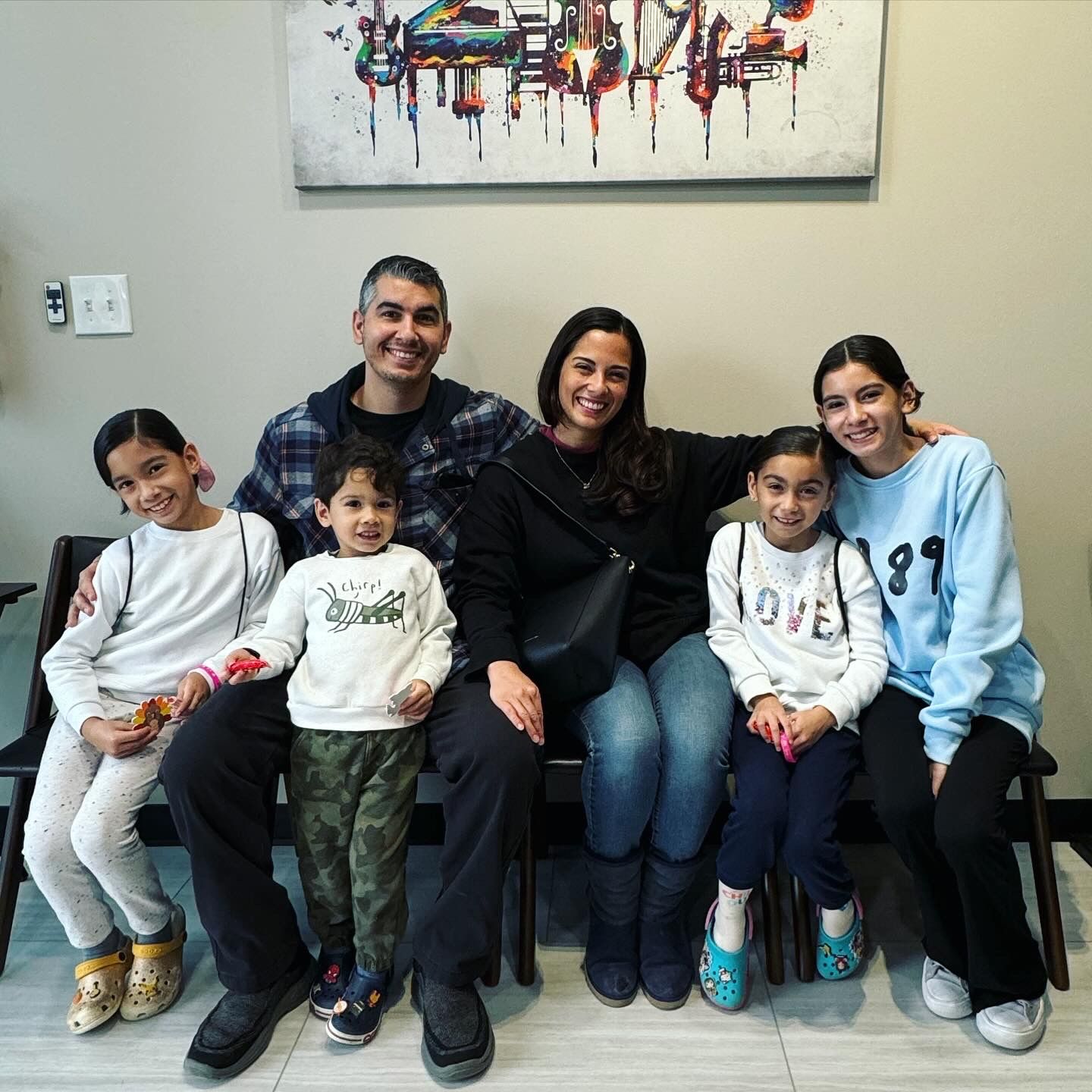 A family is posing for a picture while sitting on a bench.