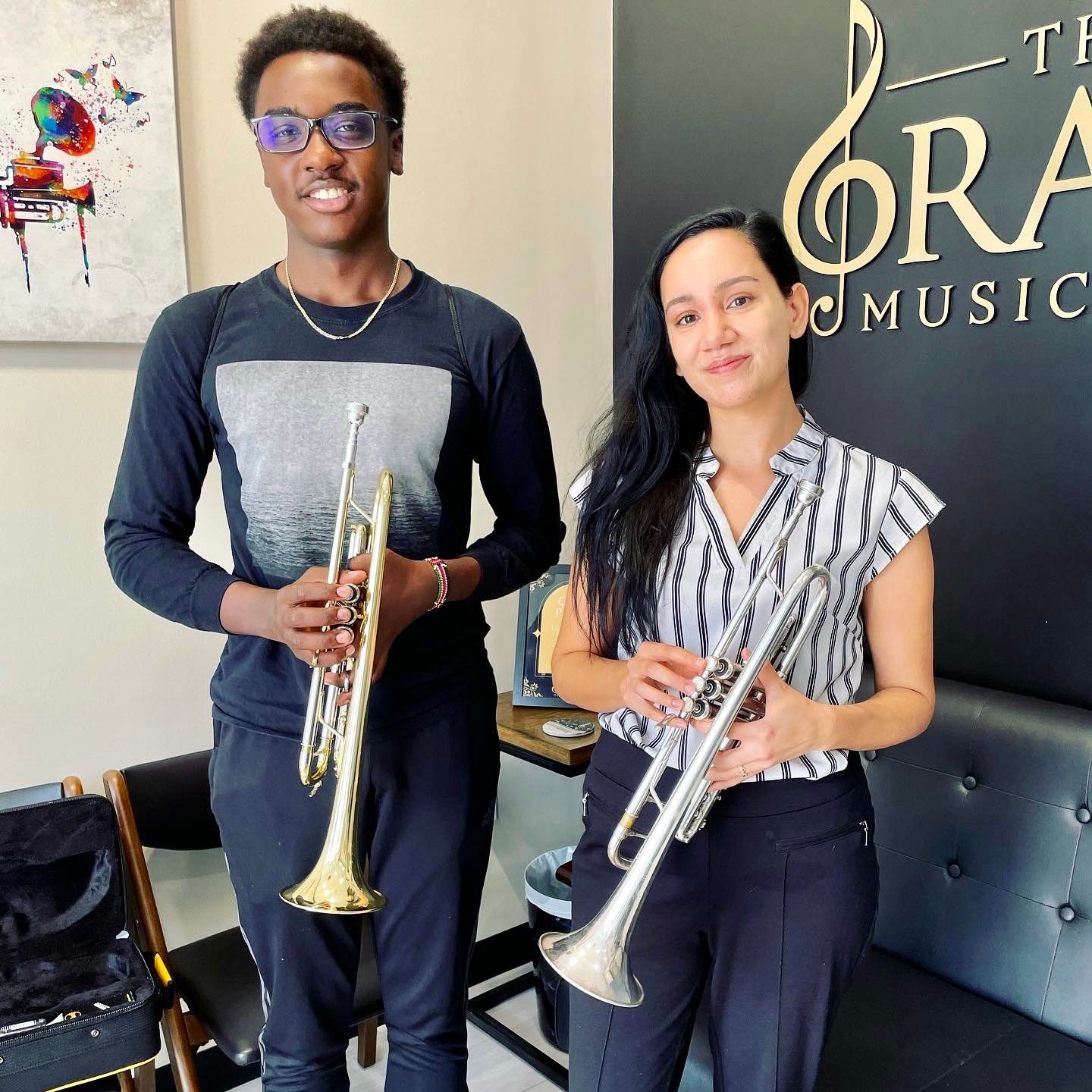 A man and a woman are standing next to each other holding trumpets.