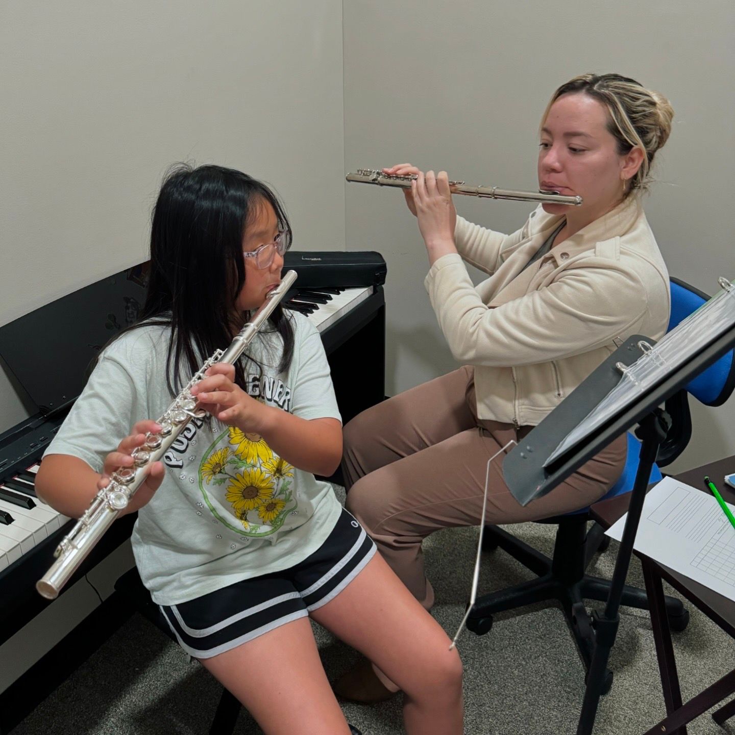 A woman is teaching a young girl how to play the flute