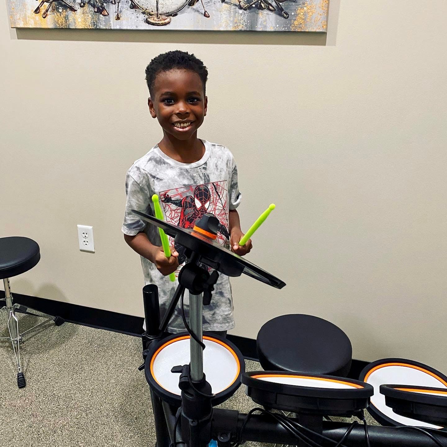 A young boy is playing a drum set in a room.