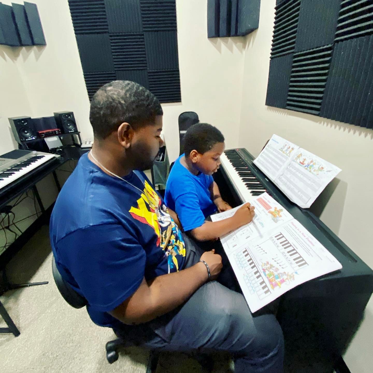 A man is teaching a young boy how to play the piano