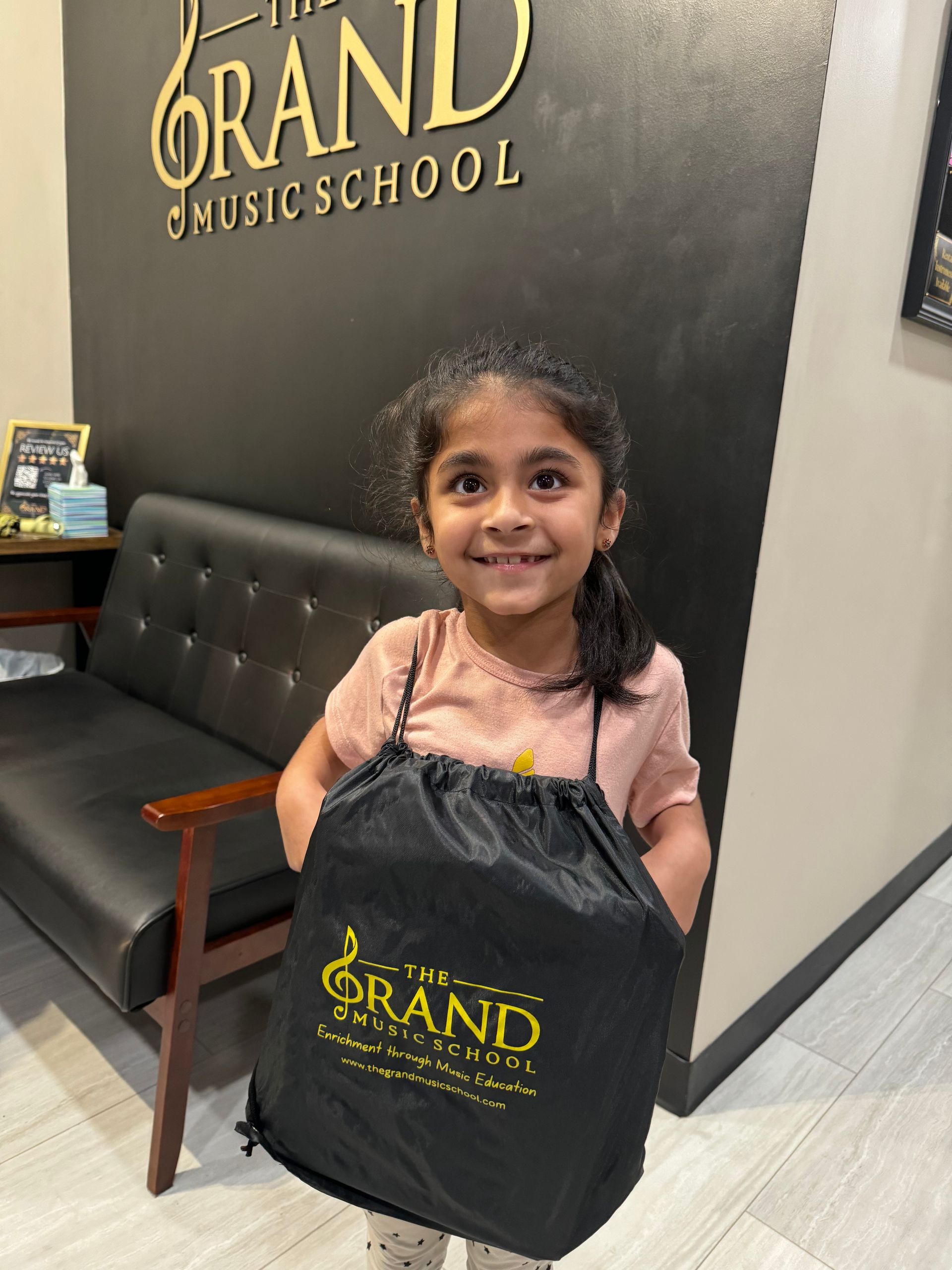 A little girl is holding a bag that says grand on it.