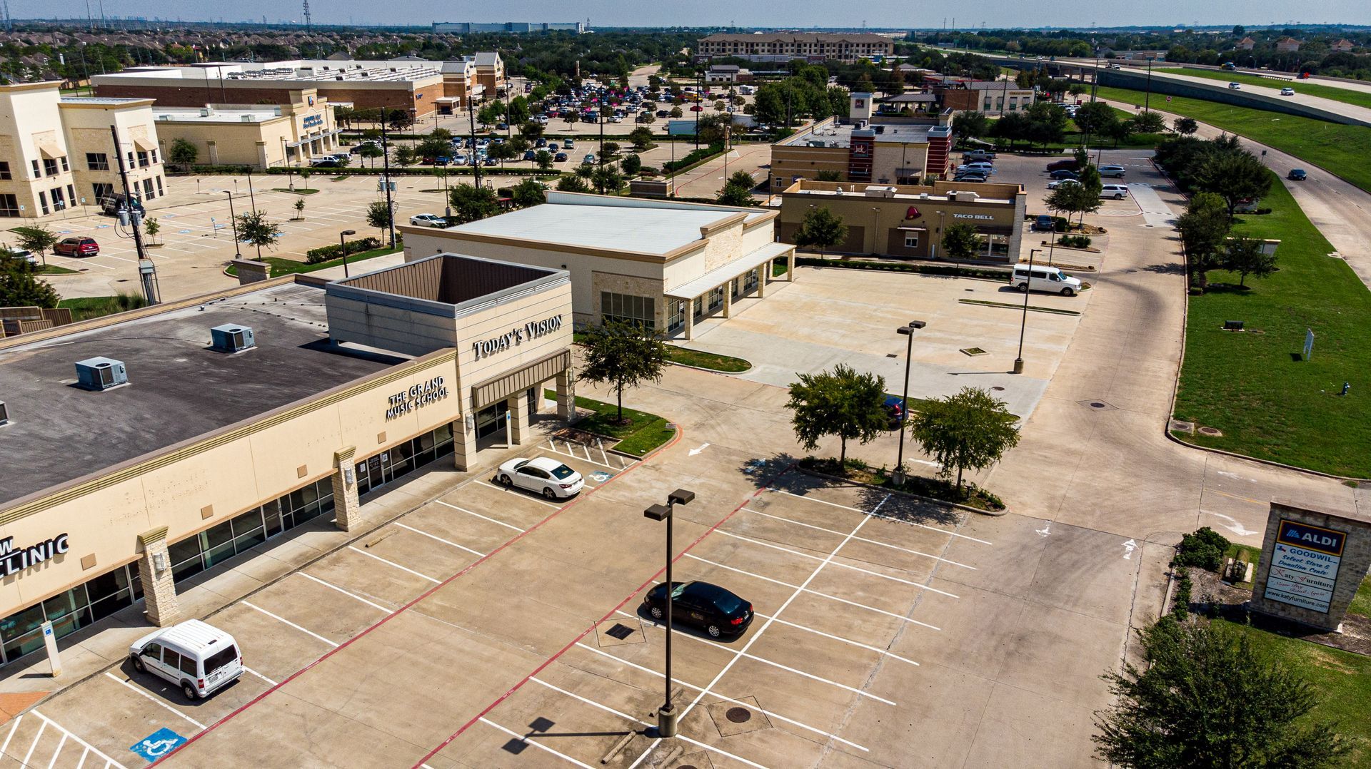 An aerial view of a parking lot with cars parked in front of a building.