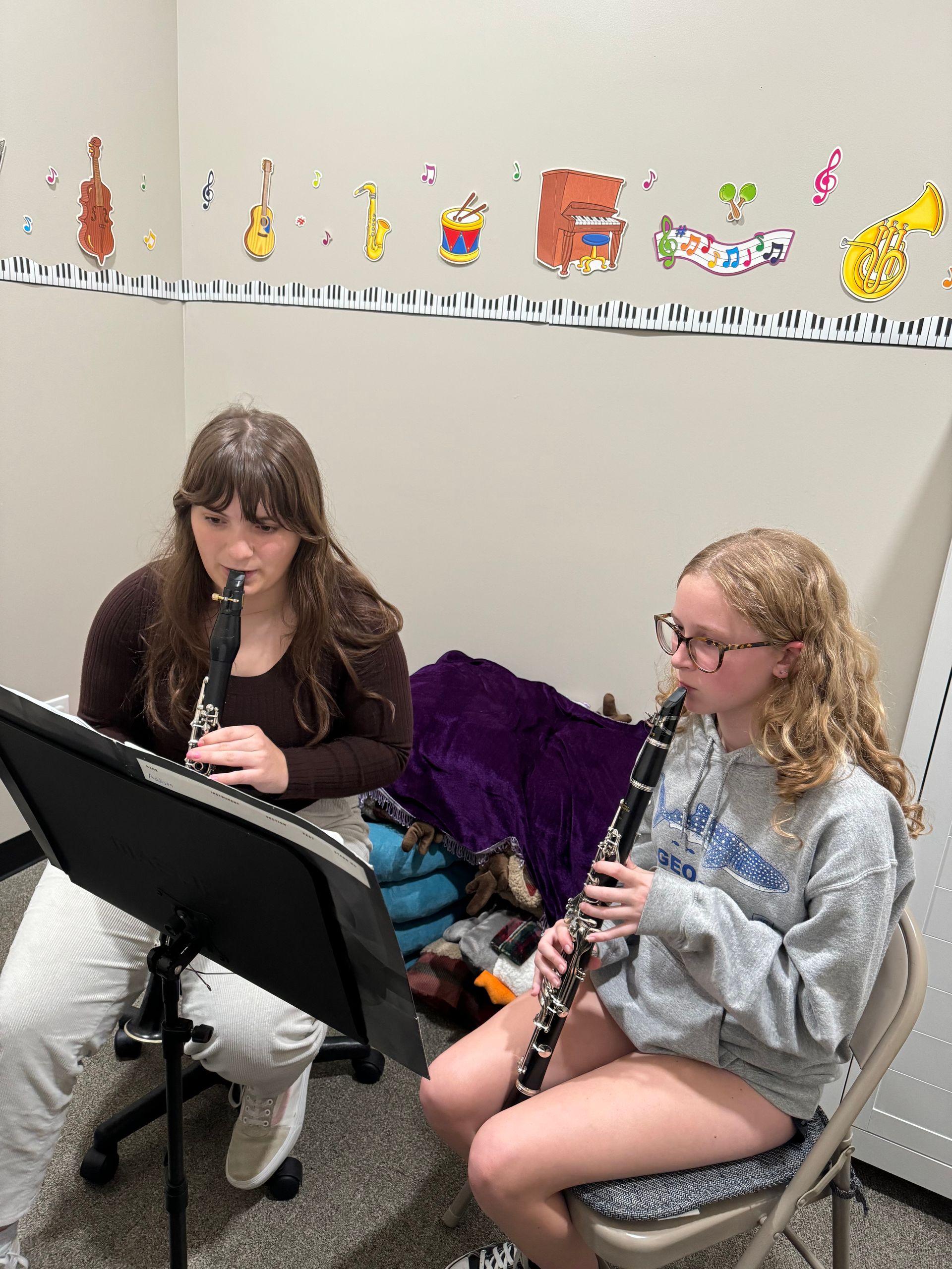 Two girls are playing clarinets in a room.