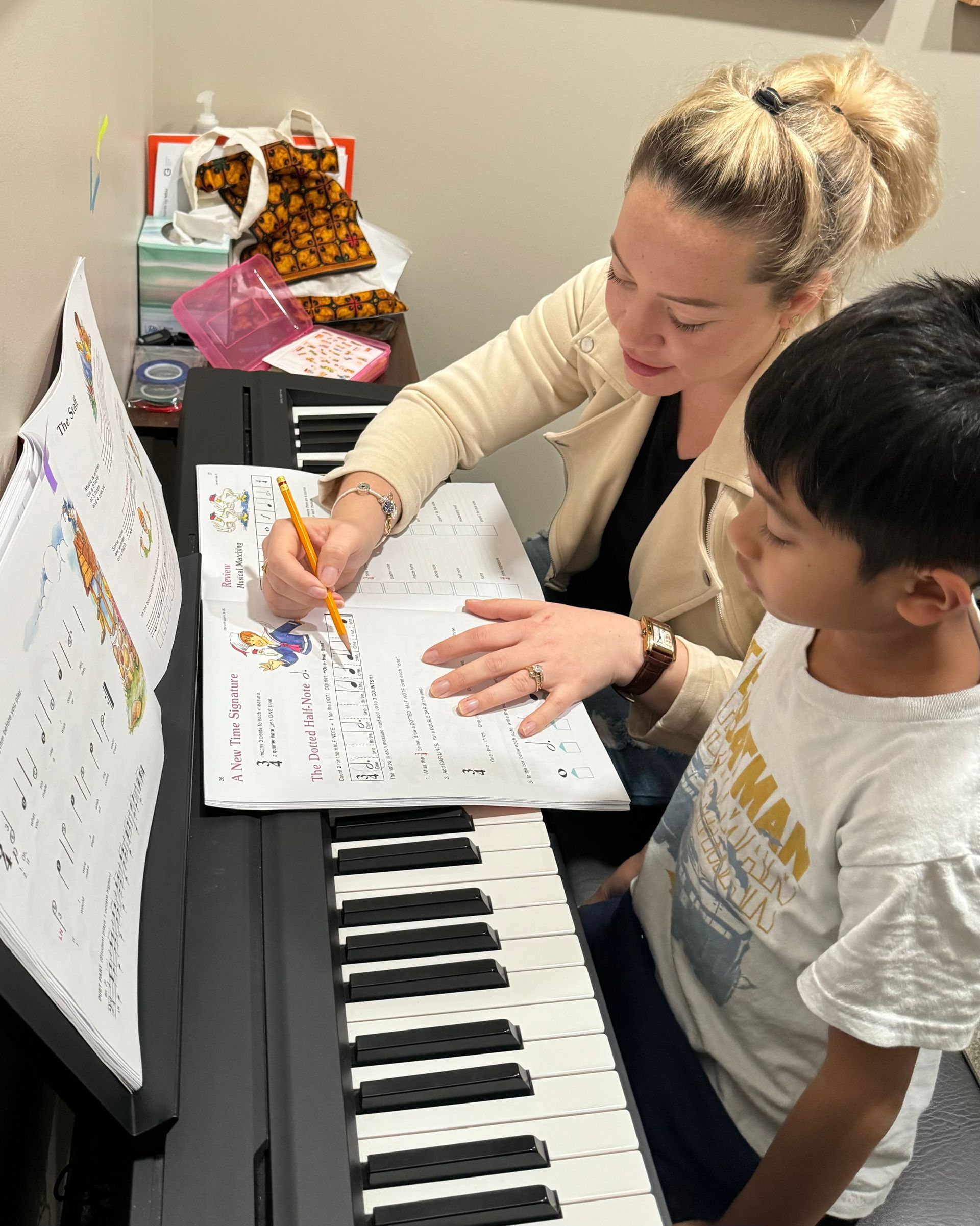 A woman is teaching a young boy how to play the piano.