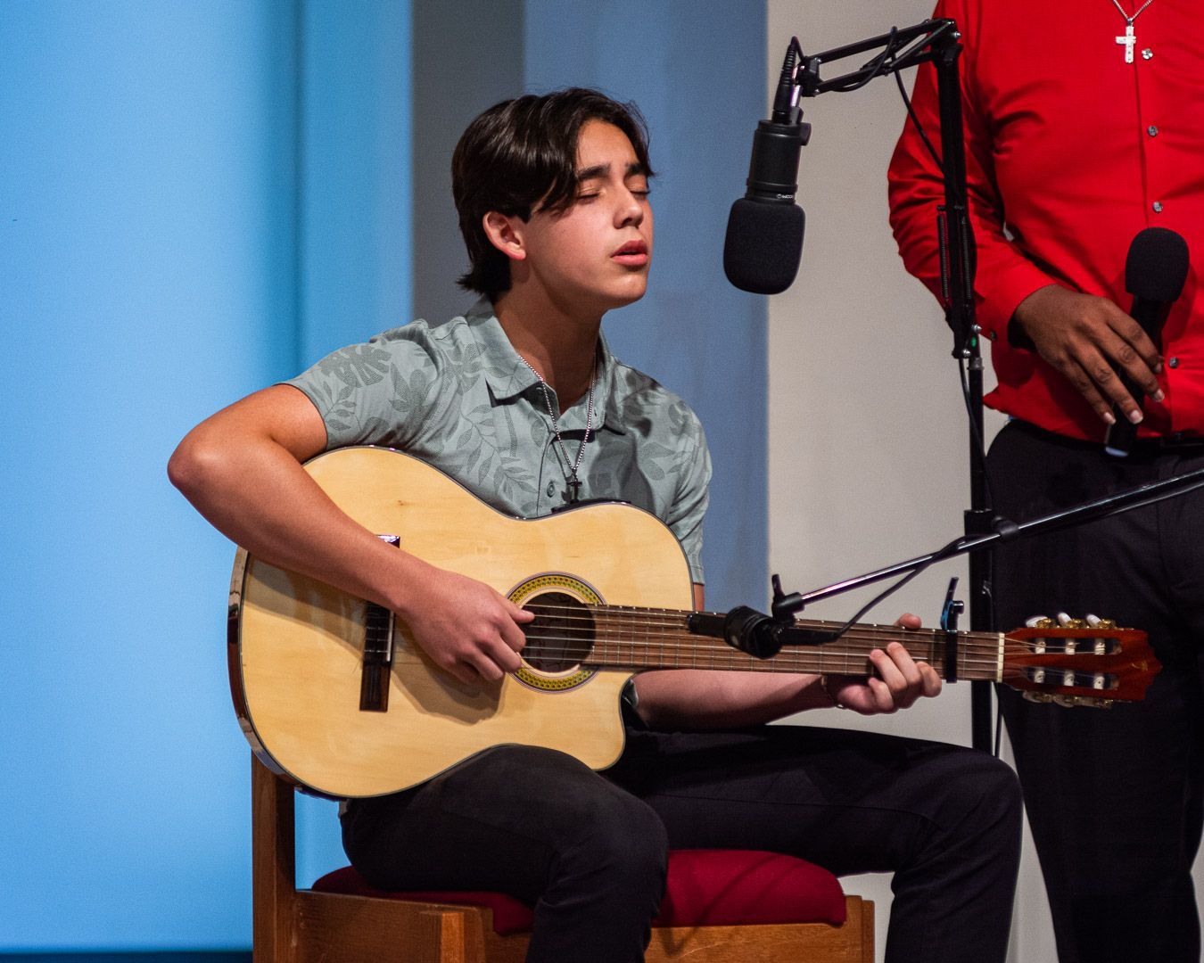 A young man is playing a guitar in front of a microphone