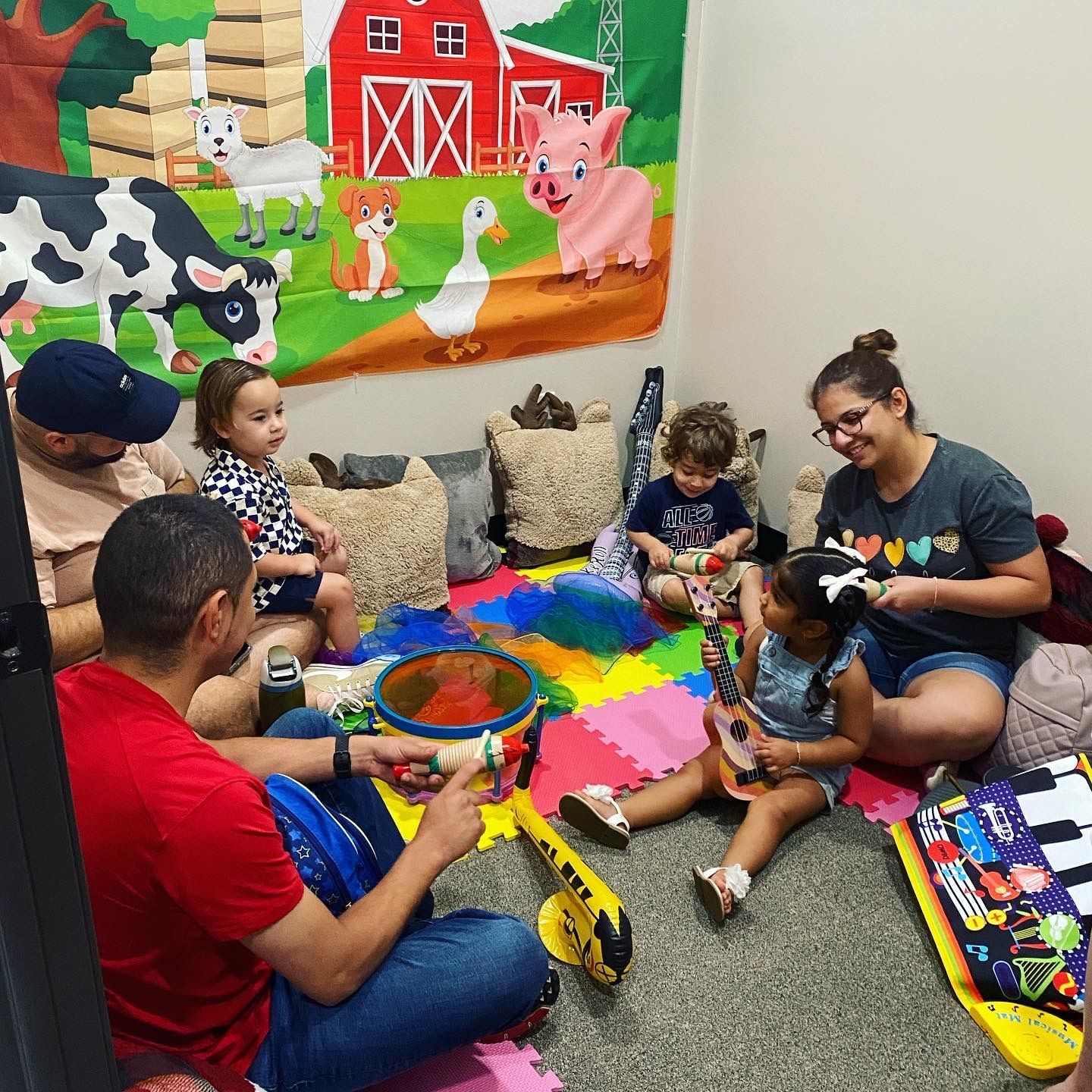 A group of people are sitting on the floor in a room with a mural on the wall.