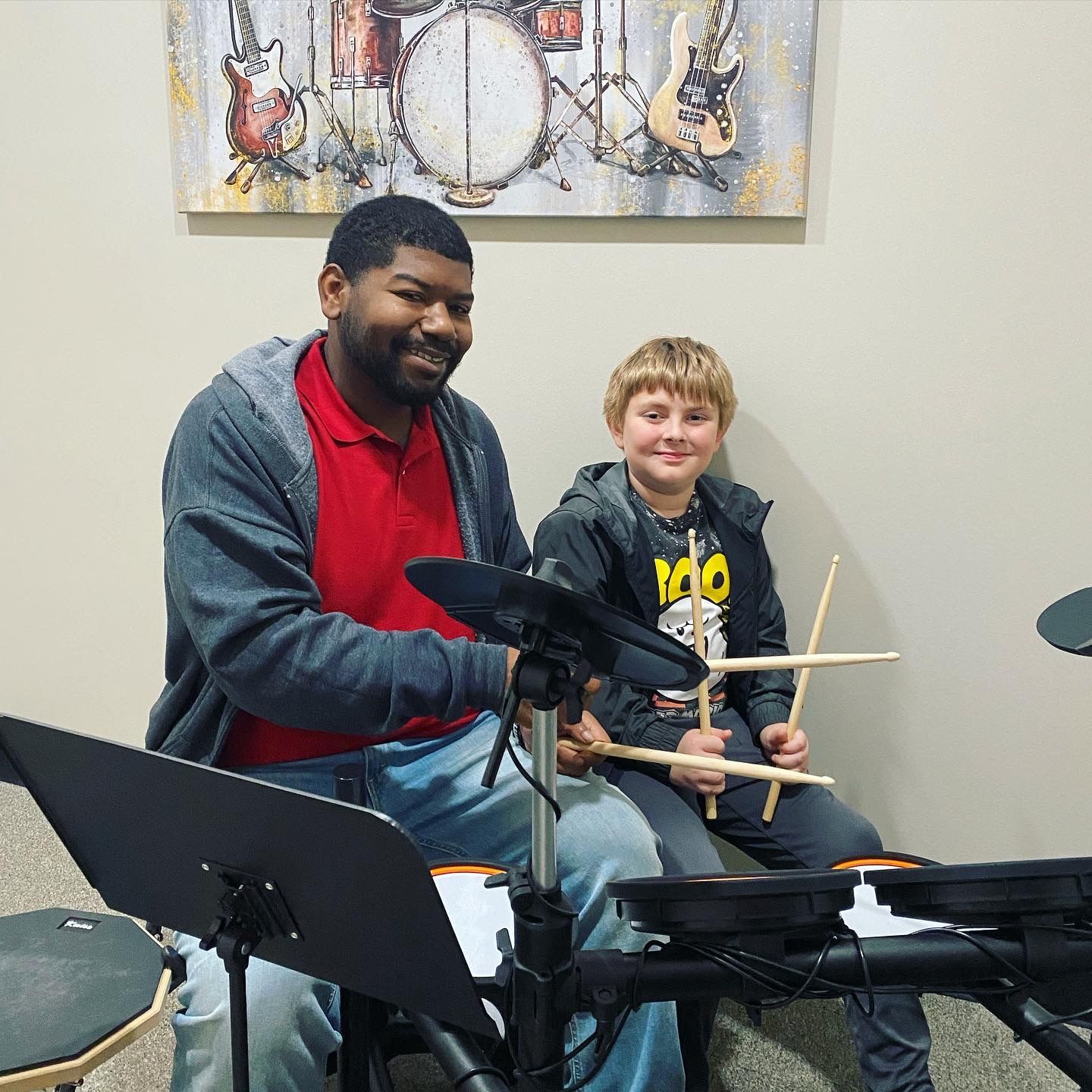 A man and a boy are playing drums in a room.