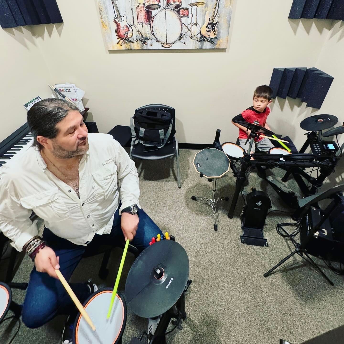 A man and a boy are playing drums in a room