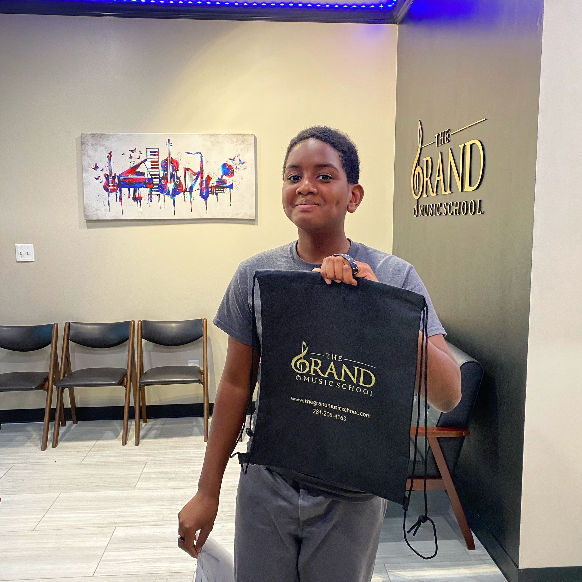 A young boy is holding a black bag that says grand on it